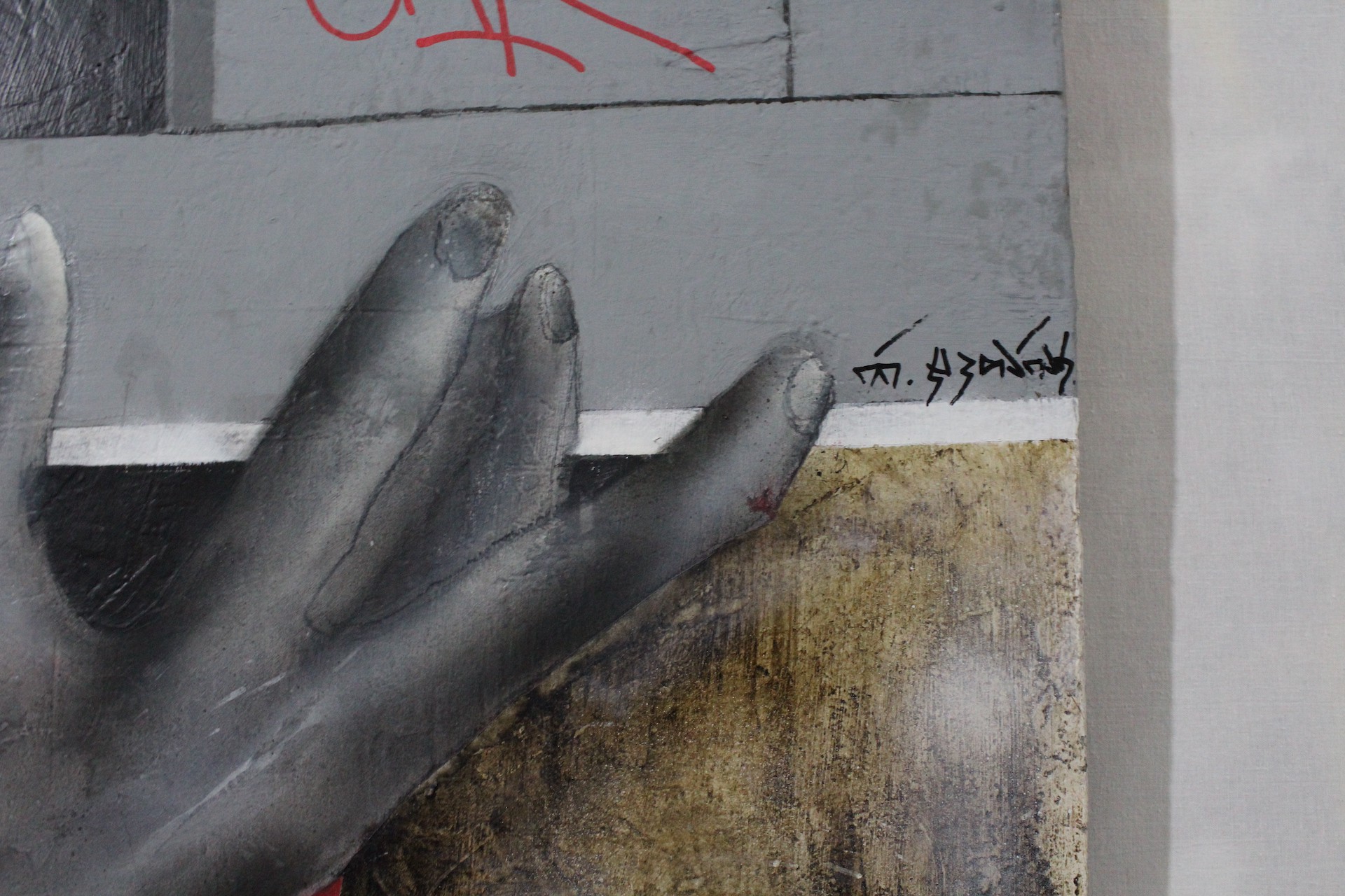 A painting of a hand on a wall with graffiti on it.