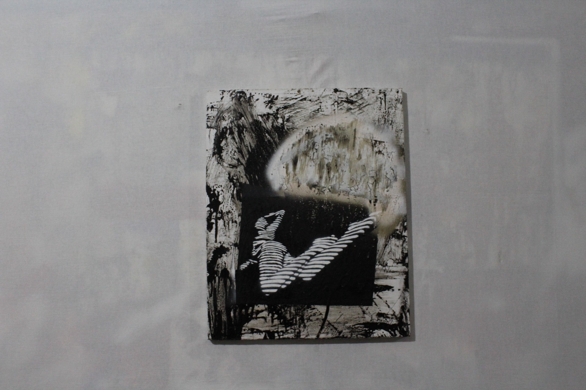 A monochromatic abstract piece featuring a striped figure against a rough, textured background.