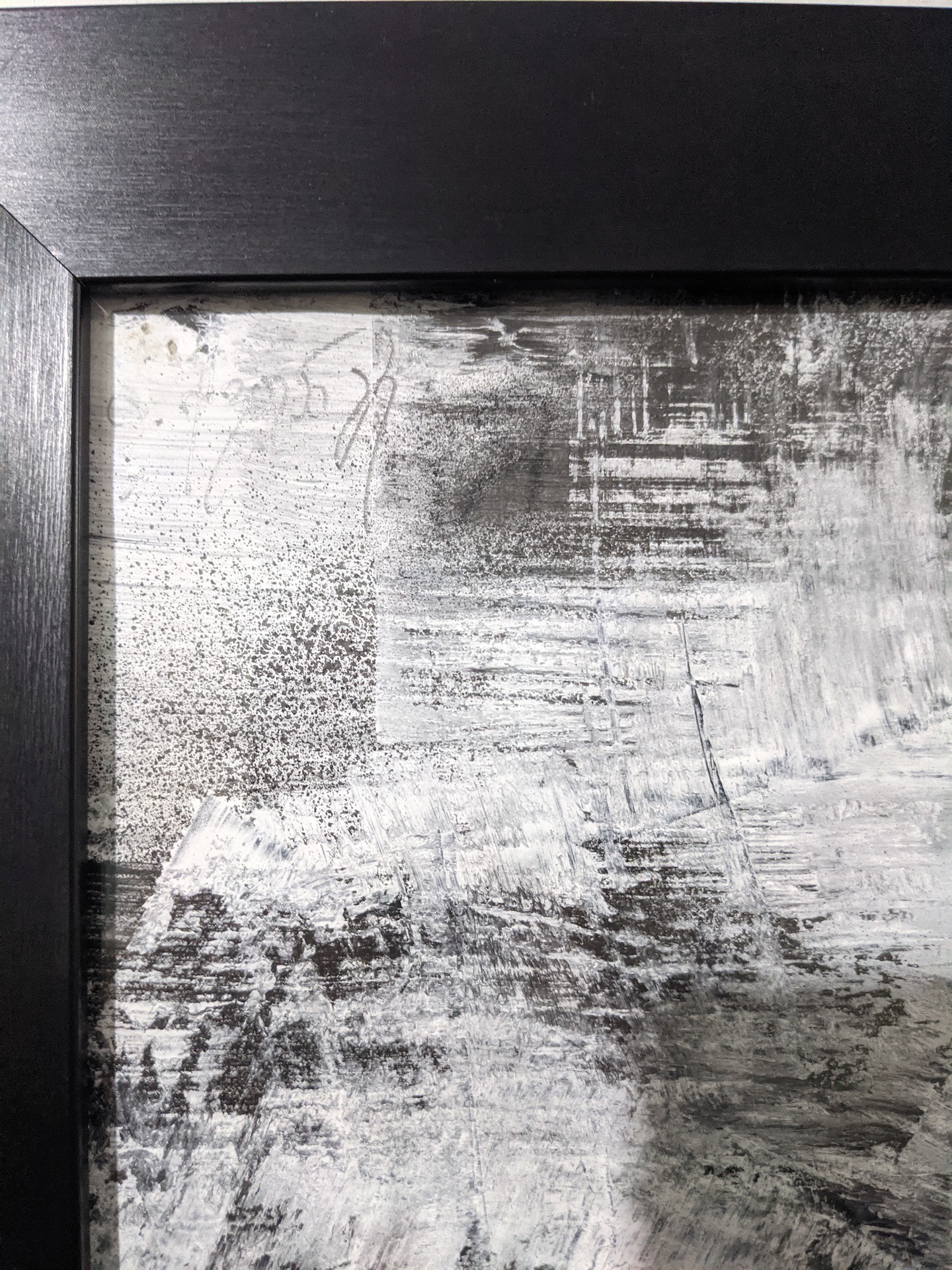 A black-framed abstract artwork featuring a monochromatic, textured composition with bold white lines.