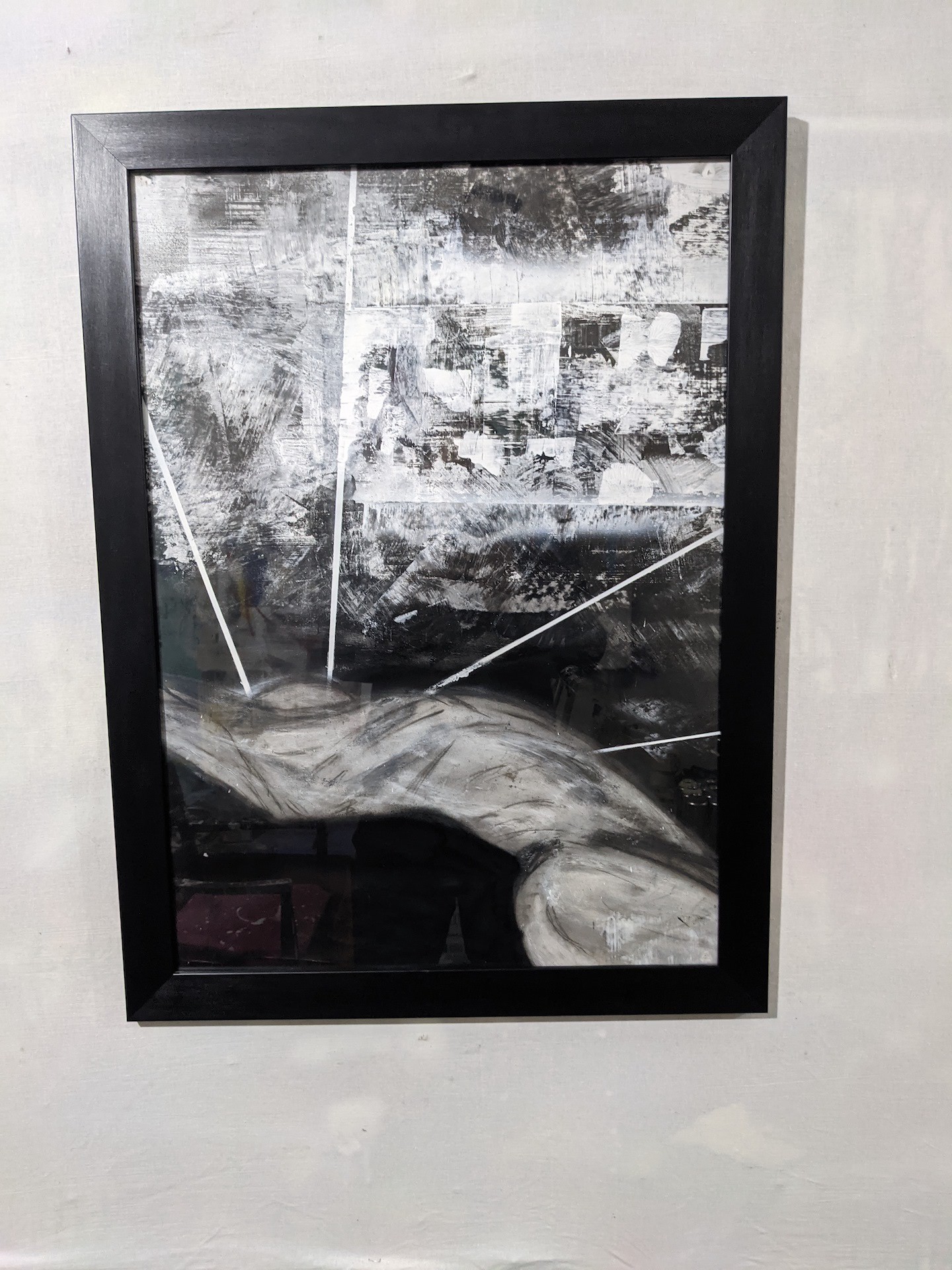 A black-framed abstract artwork featuring a monochromatic, textured composition with bold white lines.