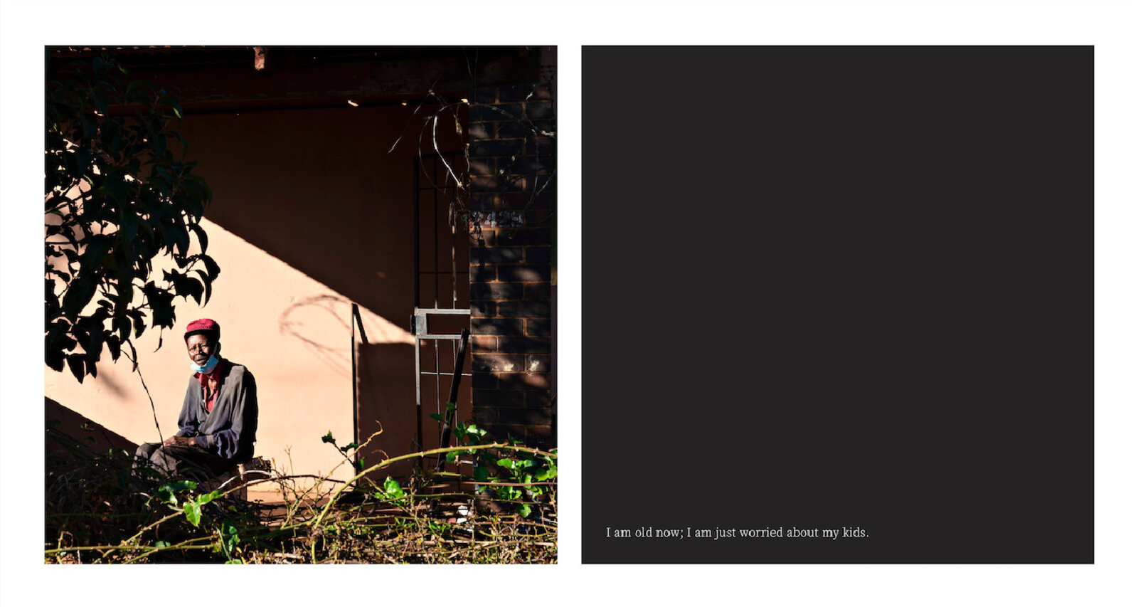 A man sitting on the ground in front of a building.