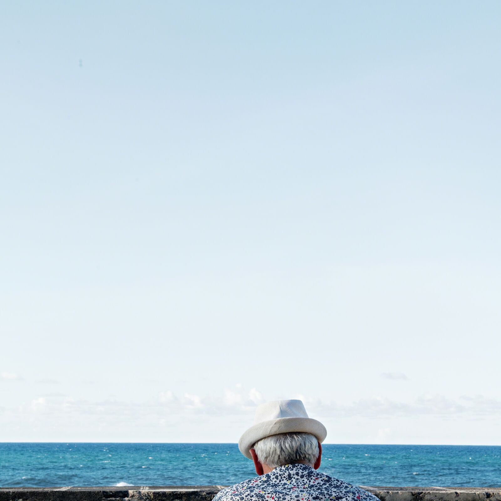 A man in a hat looking out over the ocean.