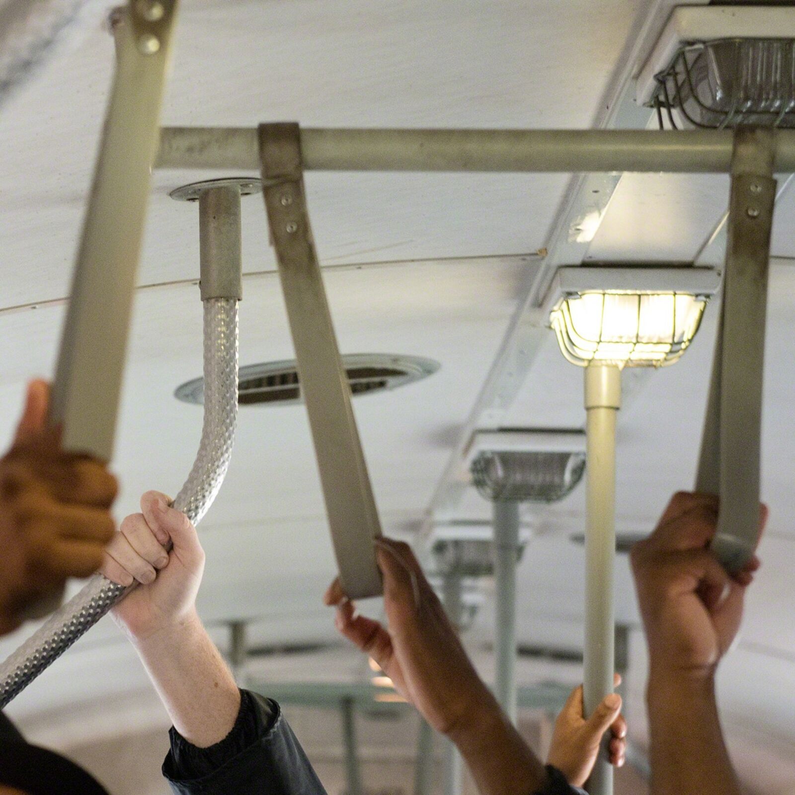 A group of people holding onto a metal pole.