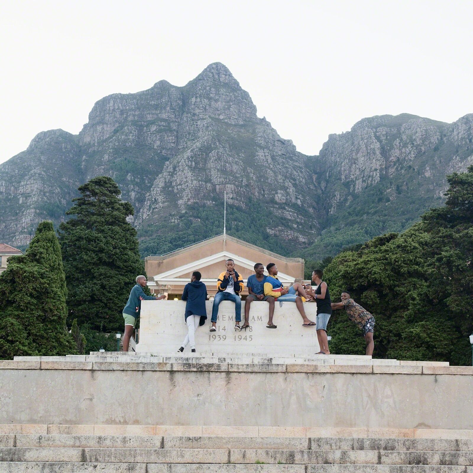 A group of people sitting on top of a stone wall.