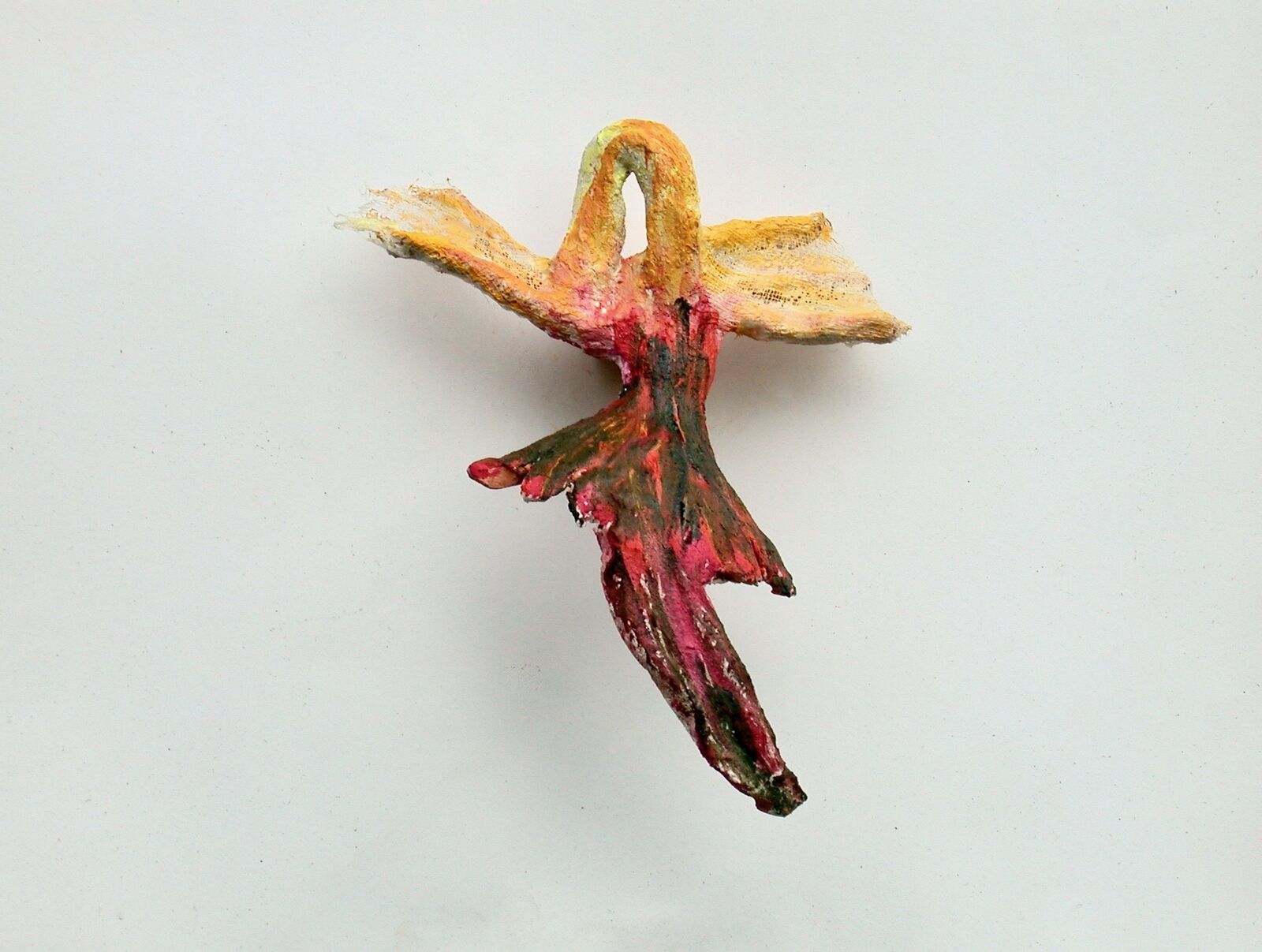 A textured, colorful sculpture of a bird in flight against a plain background.
