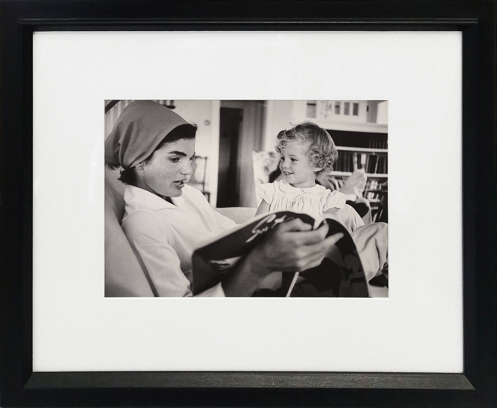 A woman sitting on a couch reading a book to a little girl.