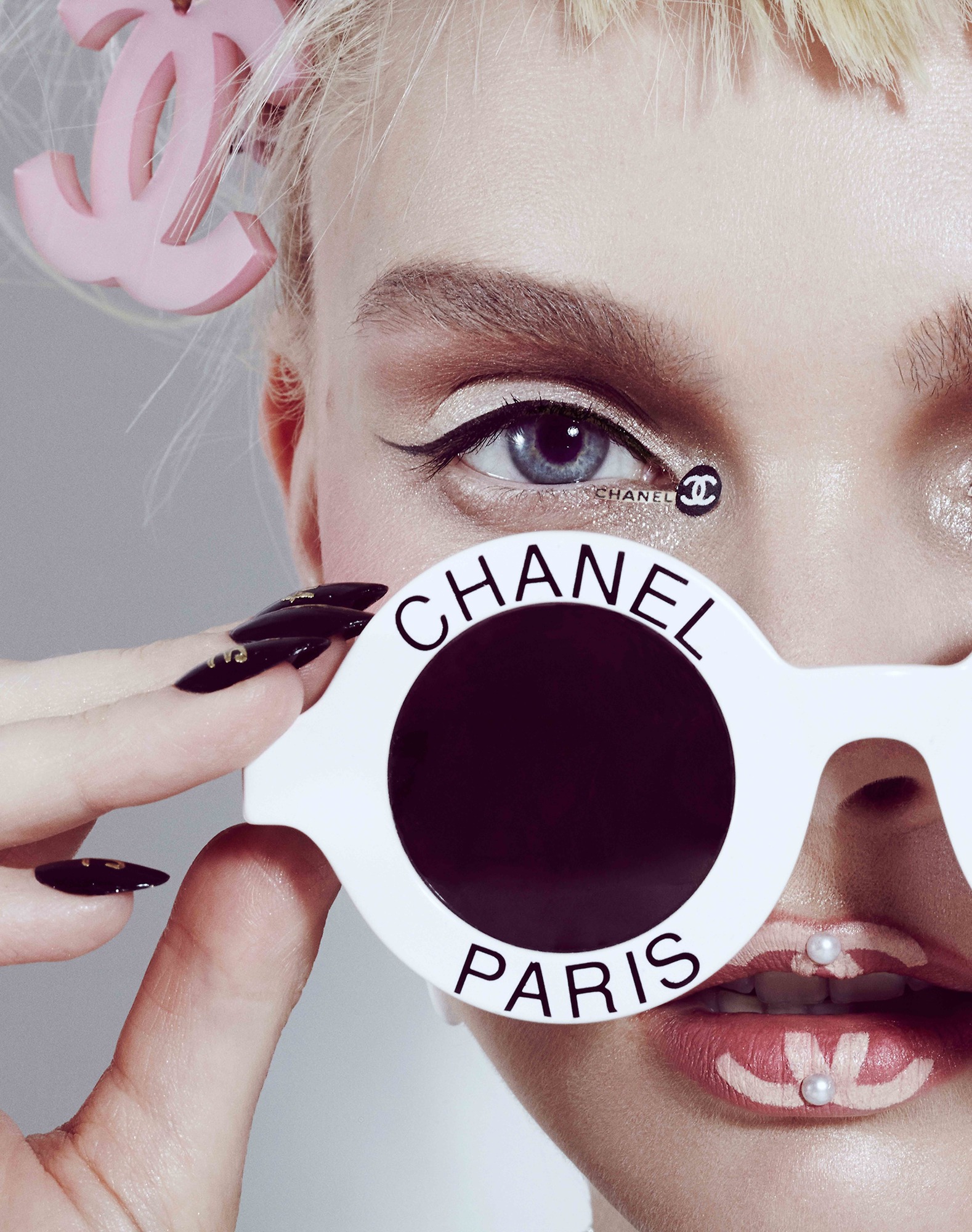 A woman holding up a pair of sunglasses with a chanel logo on it.