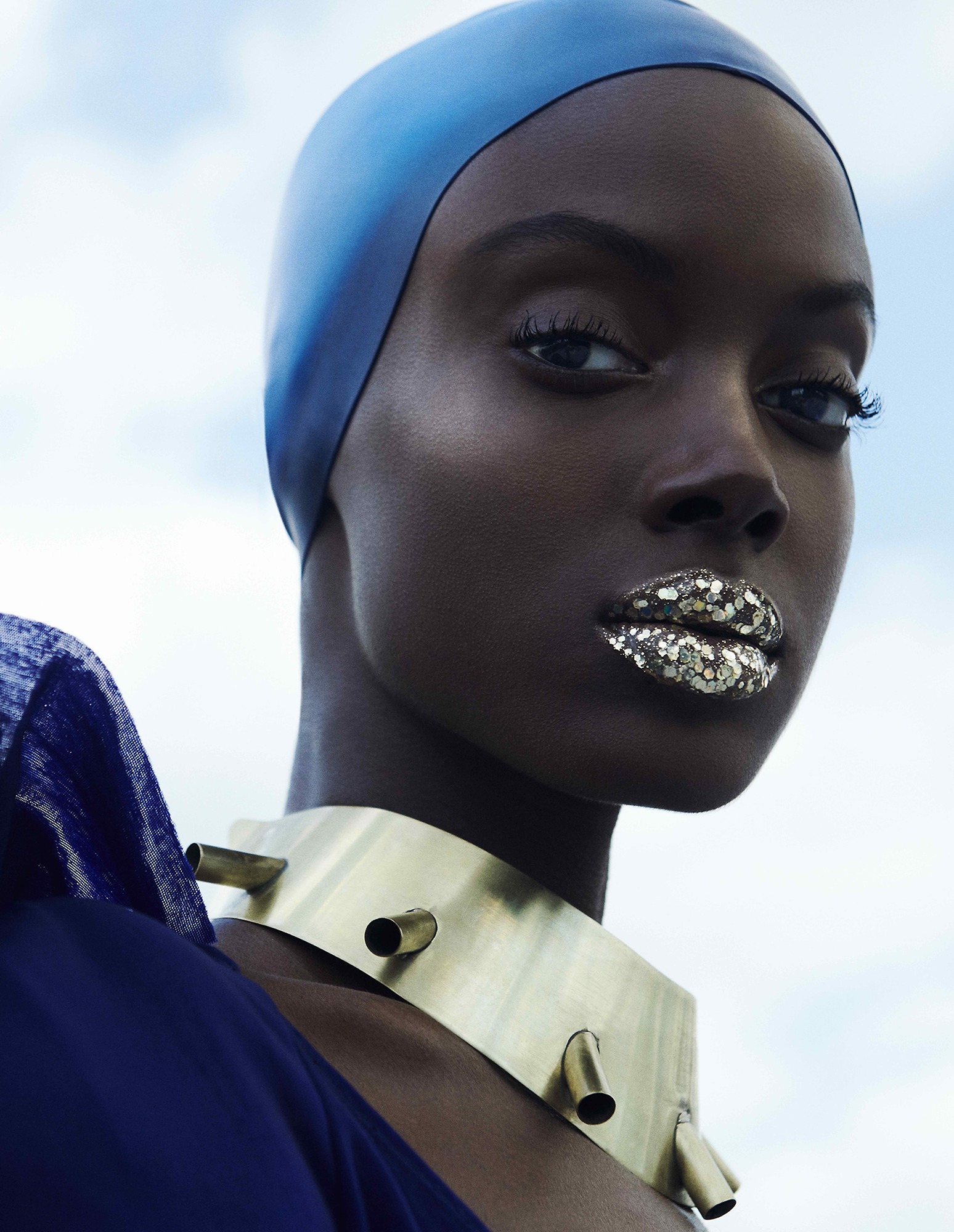 A woman wearing a blue headband and a gold choke.