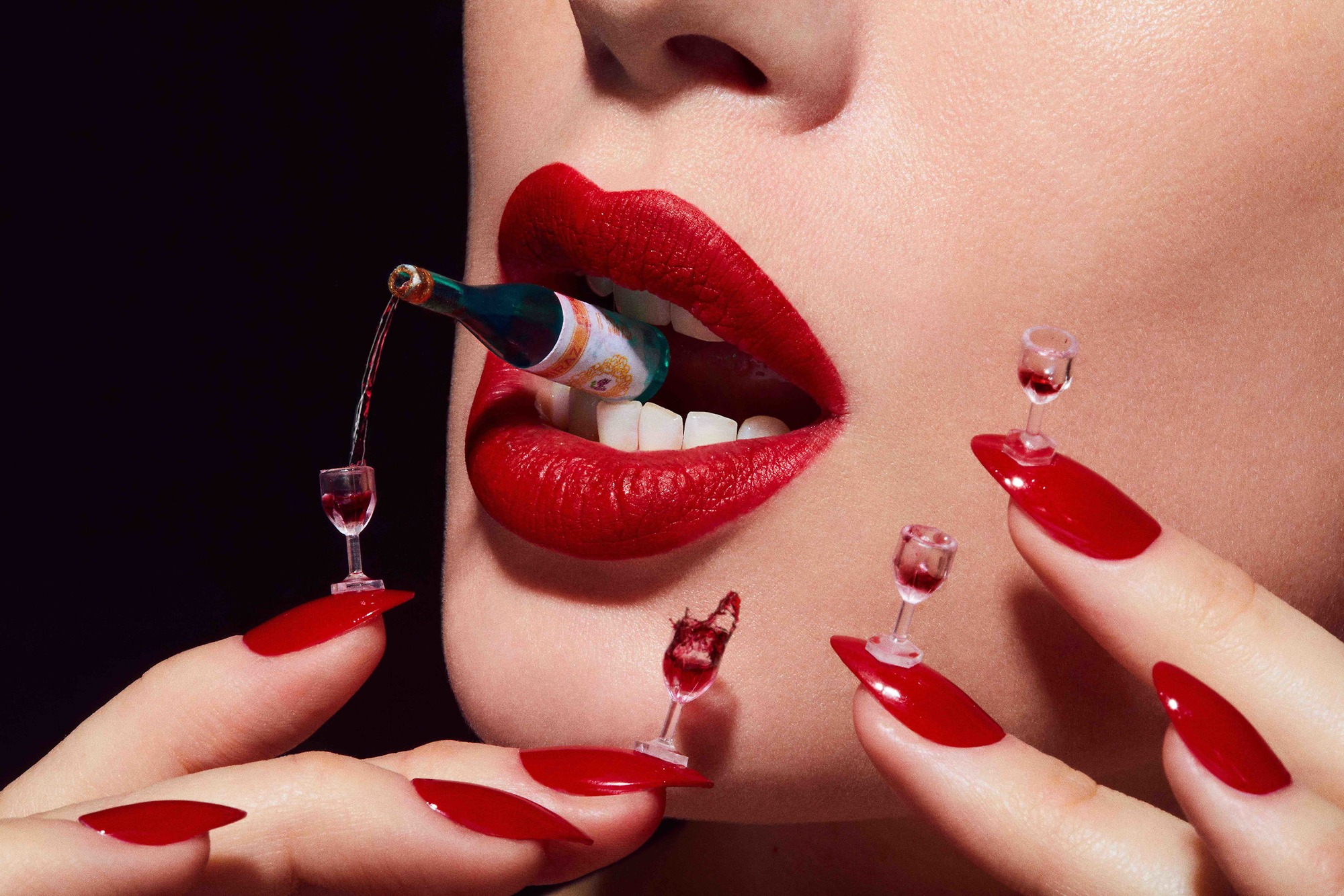 A woman with red nails and a bottle of wine in her mouth.
