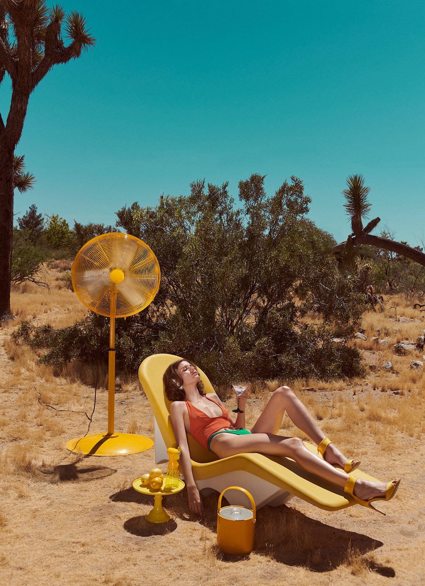 A woman laying on a yellow lounge chair in the desert.