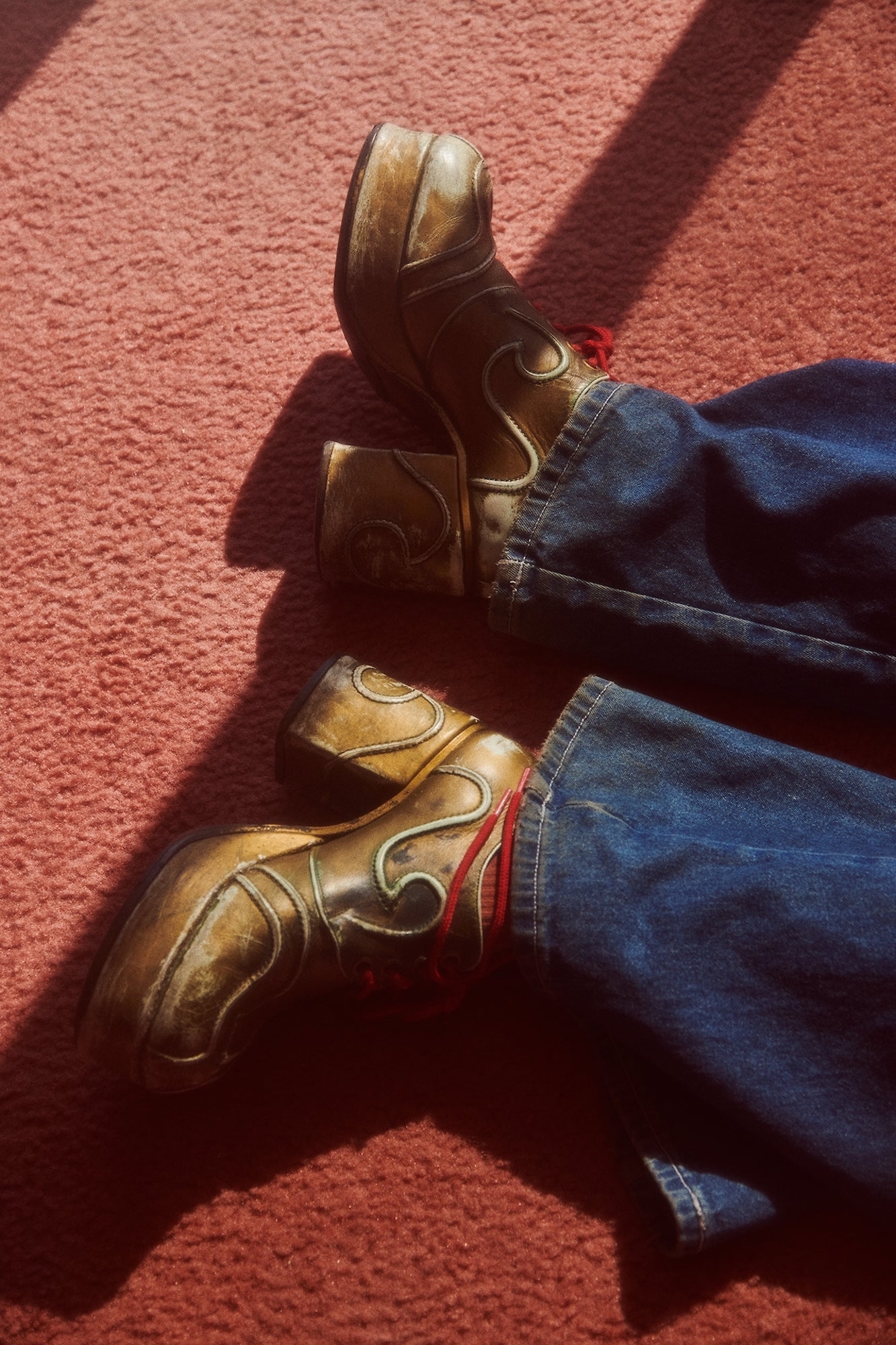 A pair of brown boots sitting on top of a red carpet.