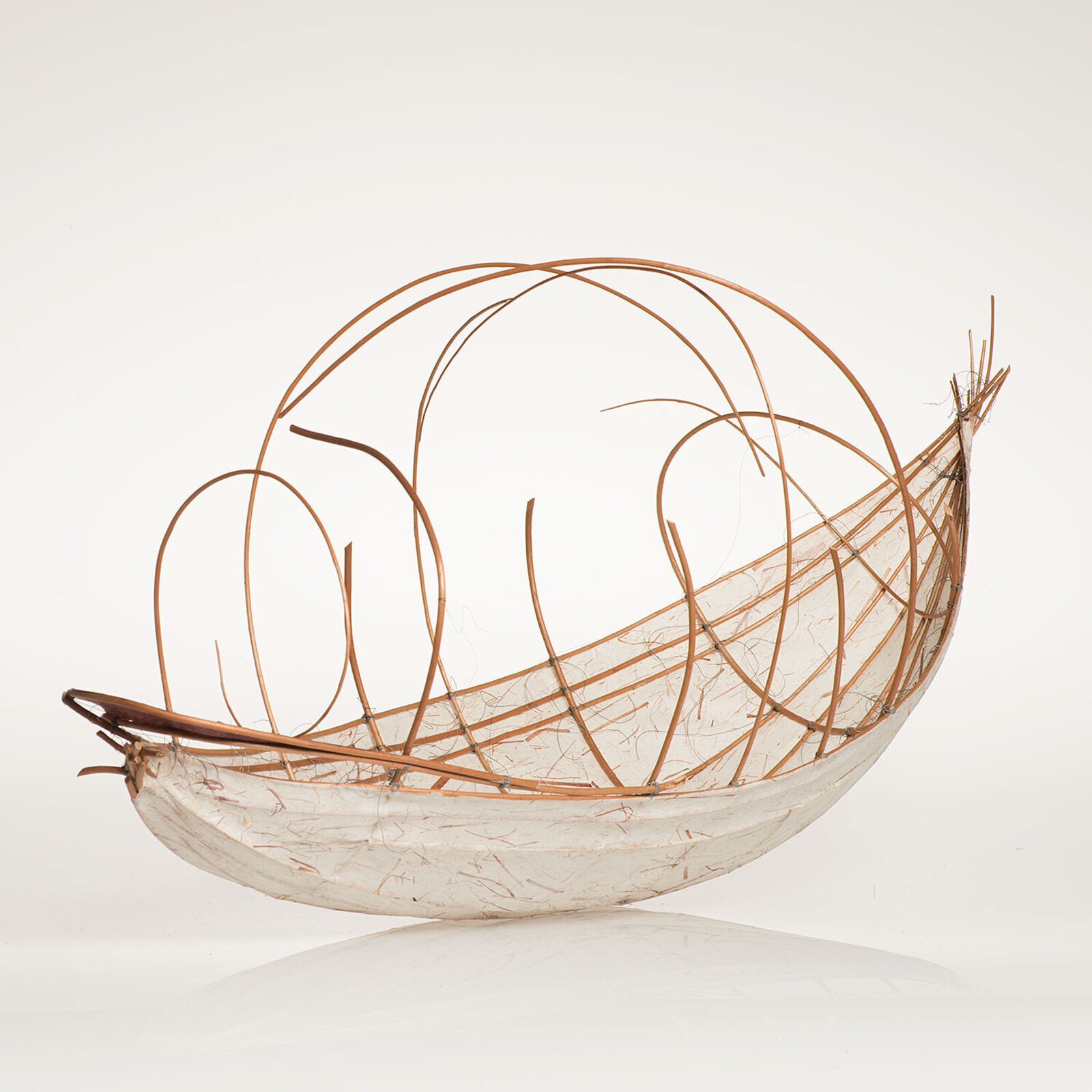 A sculptural vessel with a curved white base and an intricate framework of thin, brown, flexible rods.