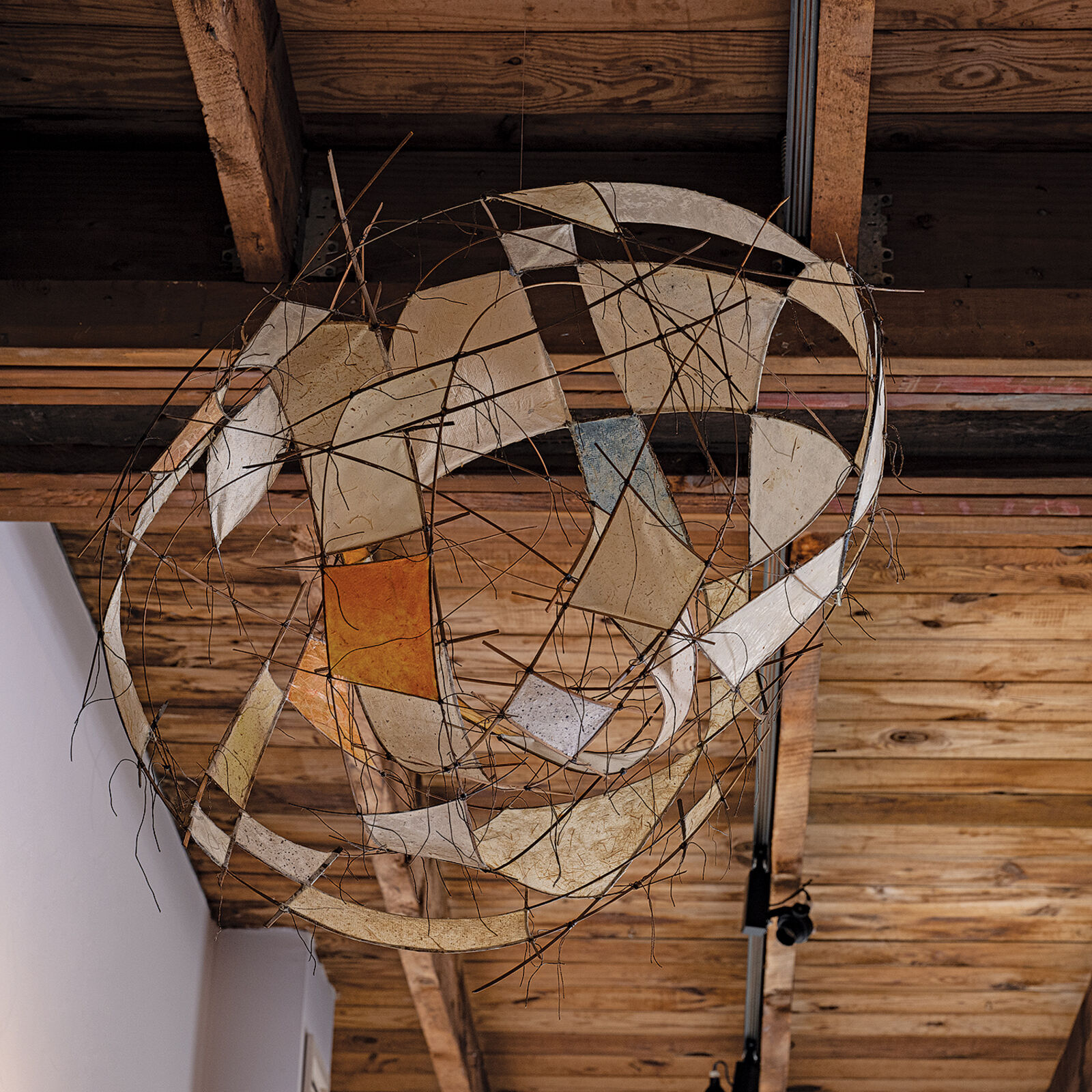 A suspended wire sculpture featuring translucent panels and abstract geometric forms.
