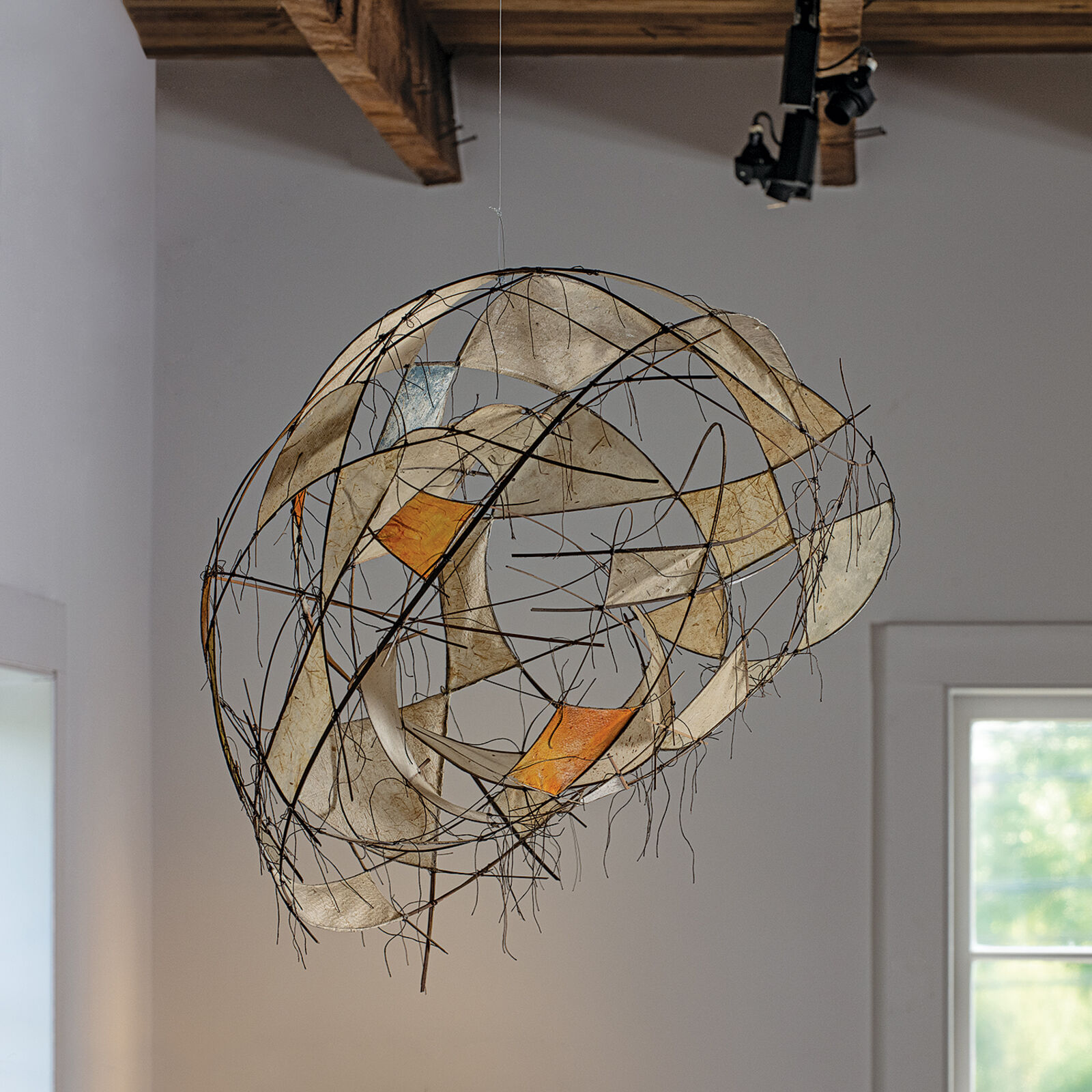A suspended wire sculpture featuring translucent panels and abstract geometric forms.
