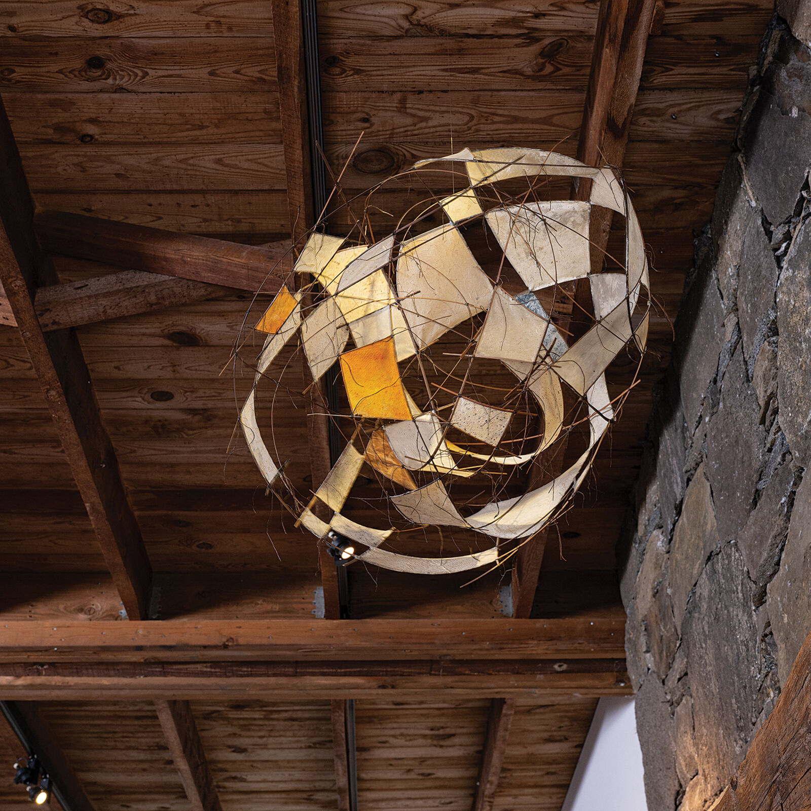 A suspended wire sculpture featuring translucent panels and abstract geometric forms.