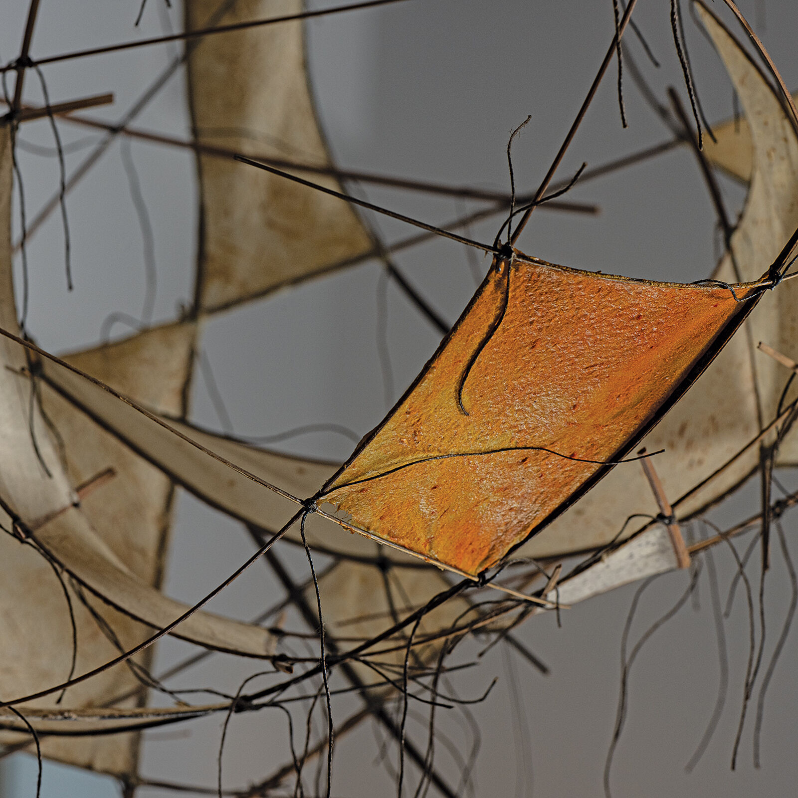 A suspended wire sculpture featuring translucent panels and abstract geometric forms.