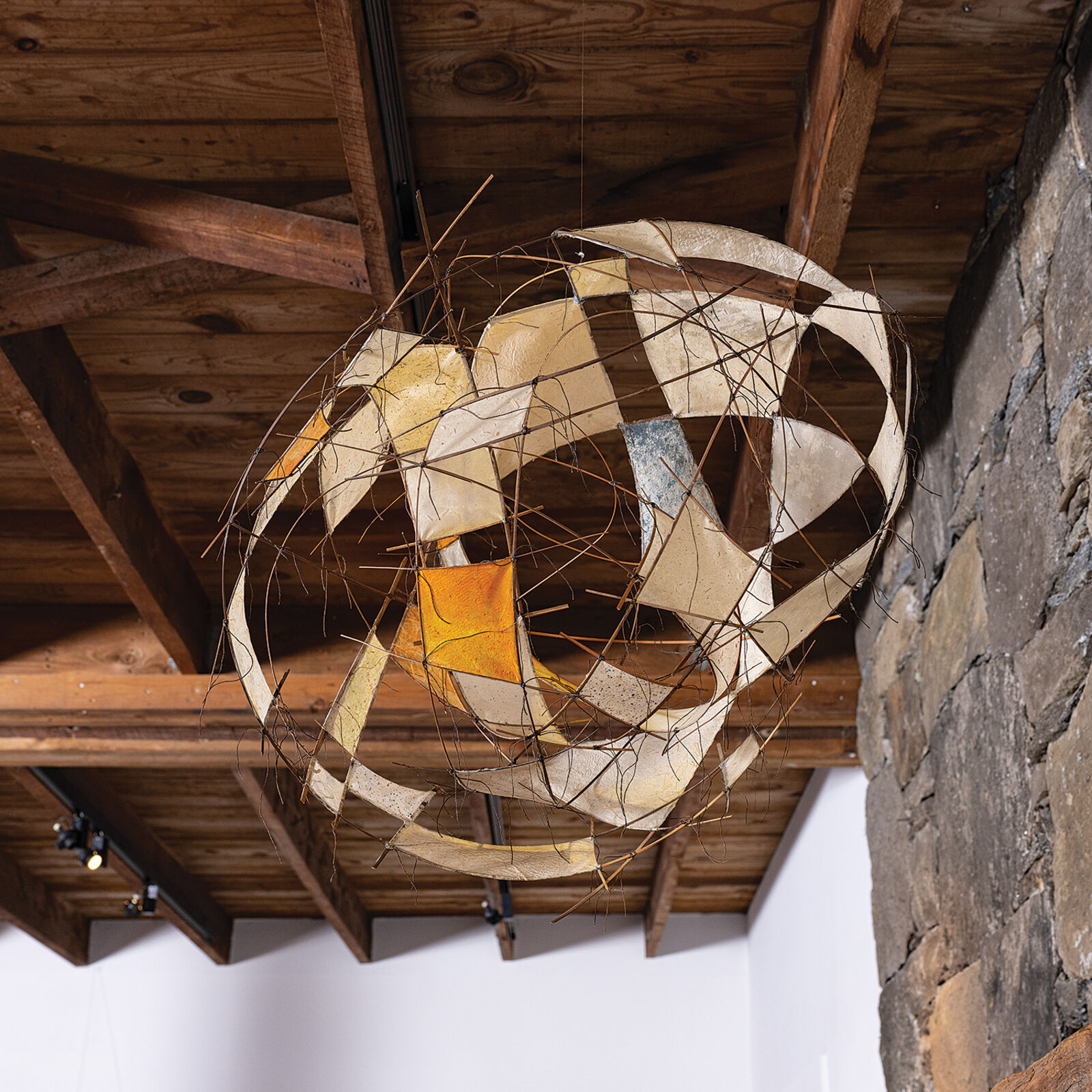 A suspended wire sculpture featuring translucent panels and abstract geometric forms.