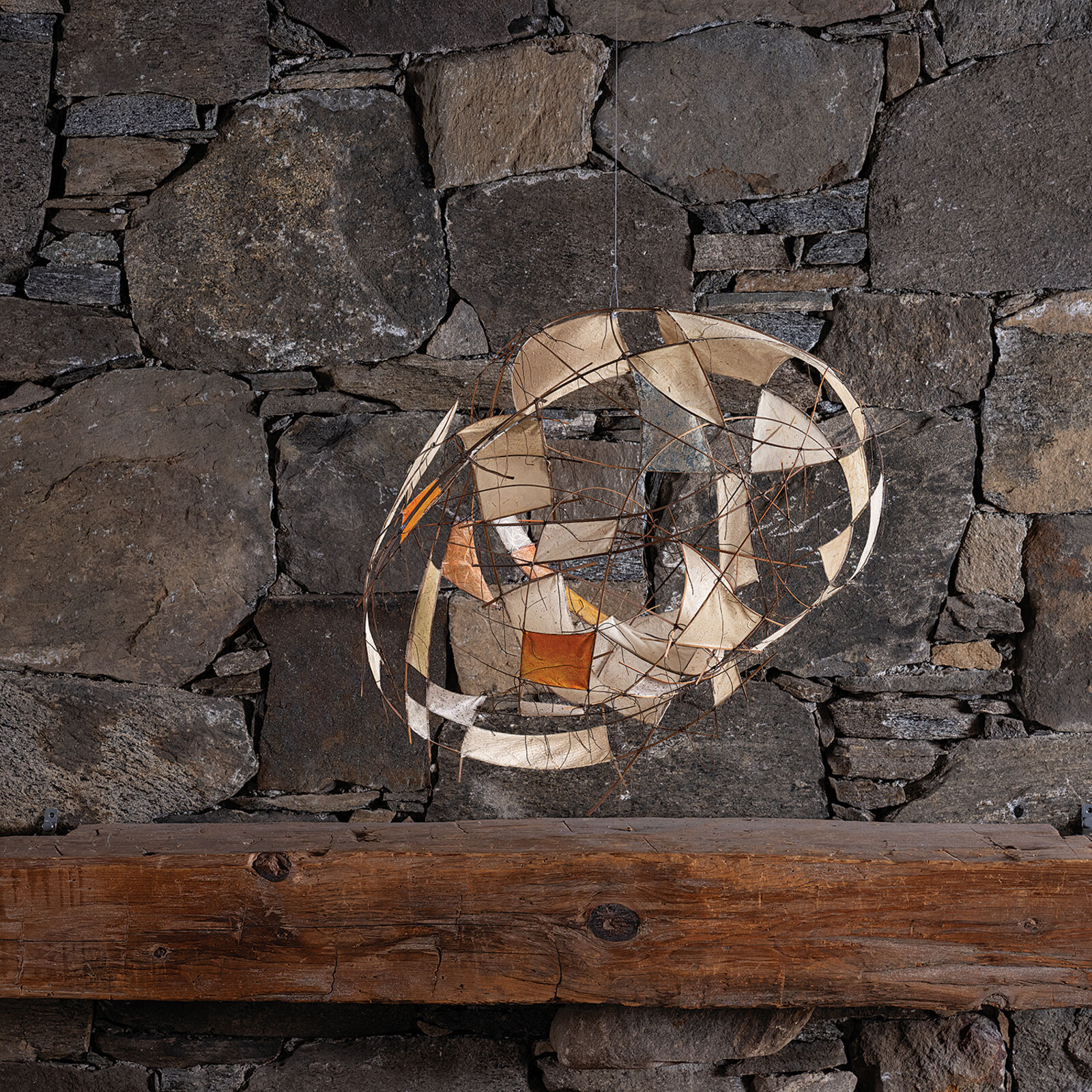 A suspended wire sculpture featuring translucent panels and abstract geometric forms.