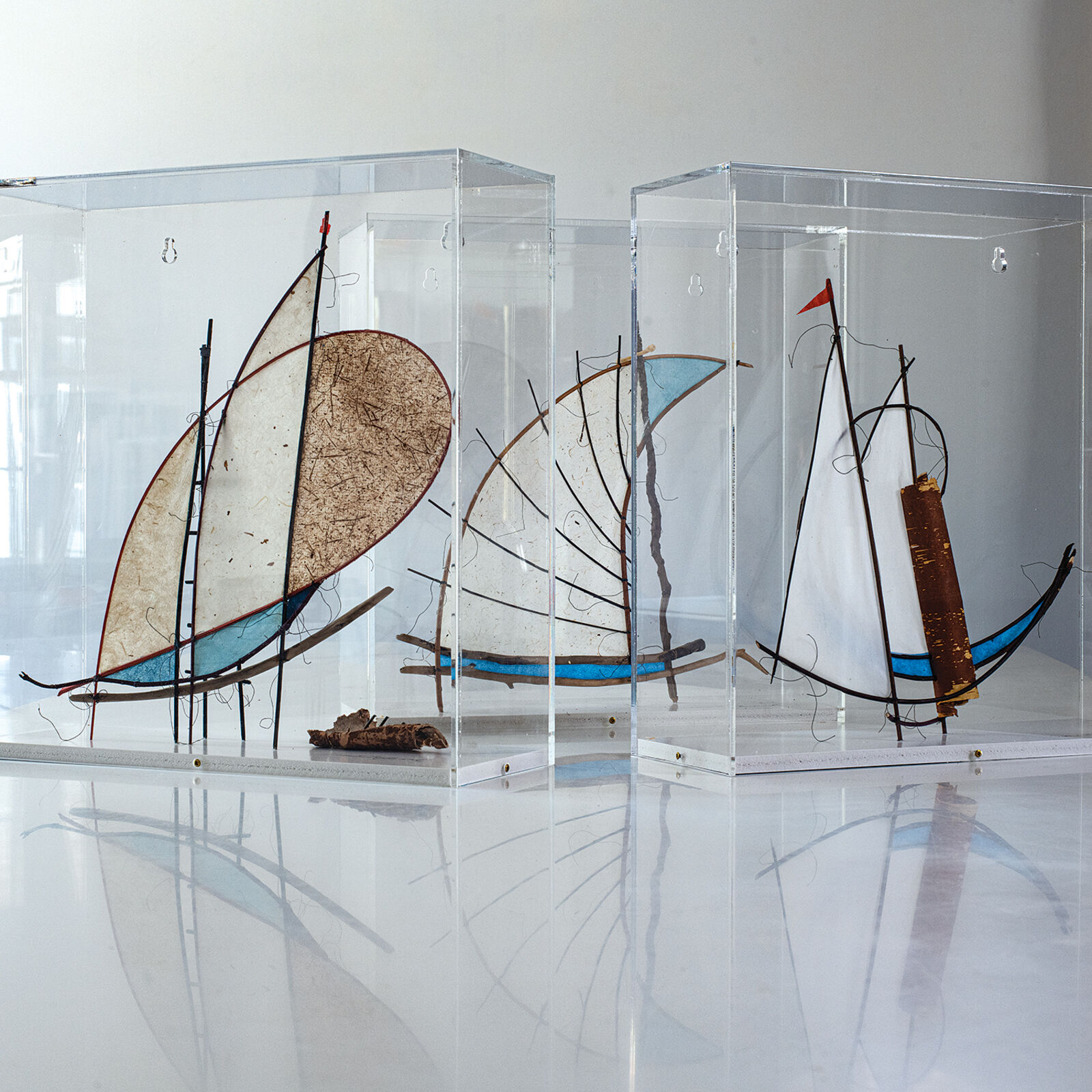 A glass sculpture of a sailboat in a clear box.