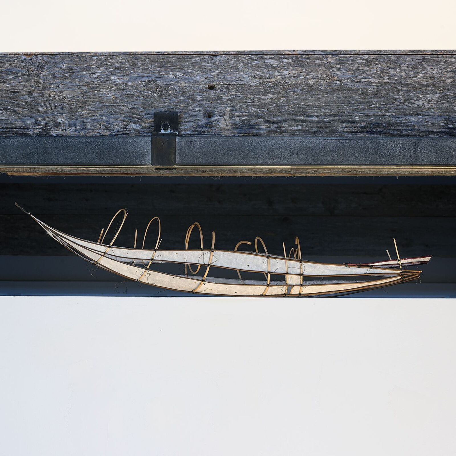A long, boat-shaped light fixture hangs beneath a weathered wooden beam.