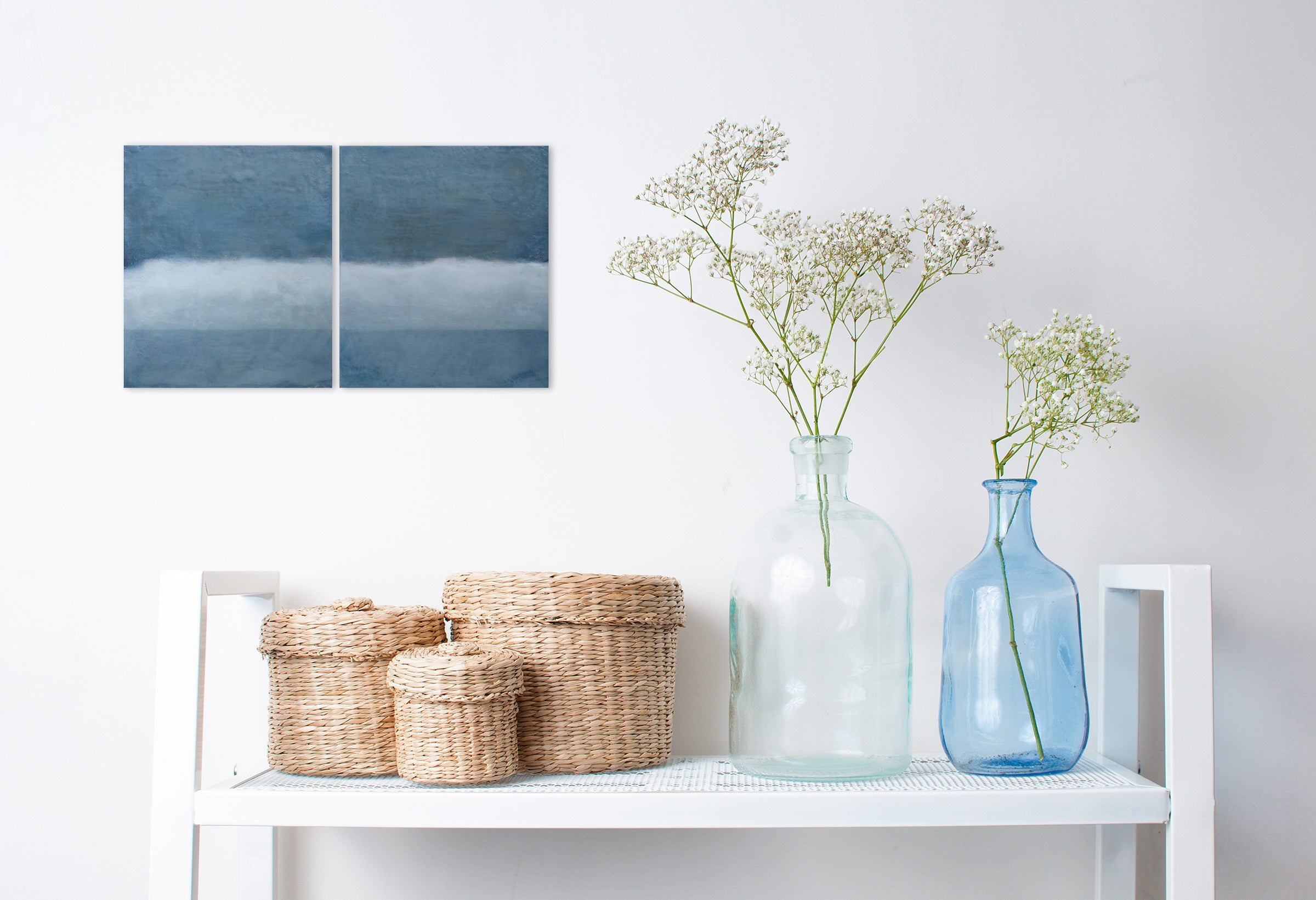 A pair of blue and white paintings on a white wall.