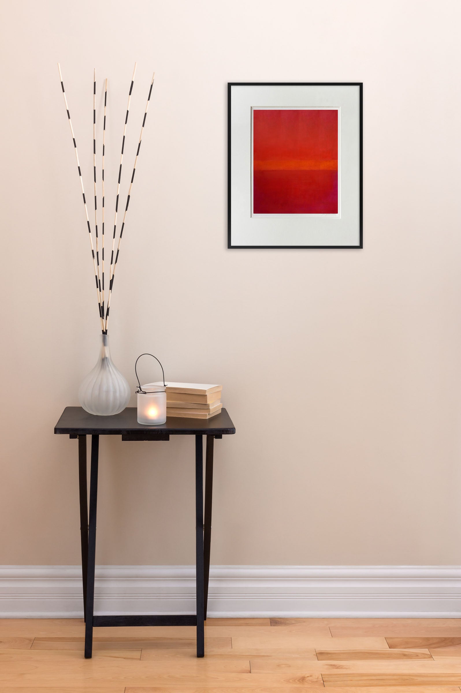 A painting of a red and orange painting in a white frame.