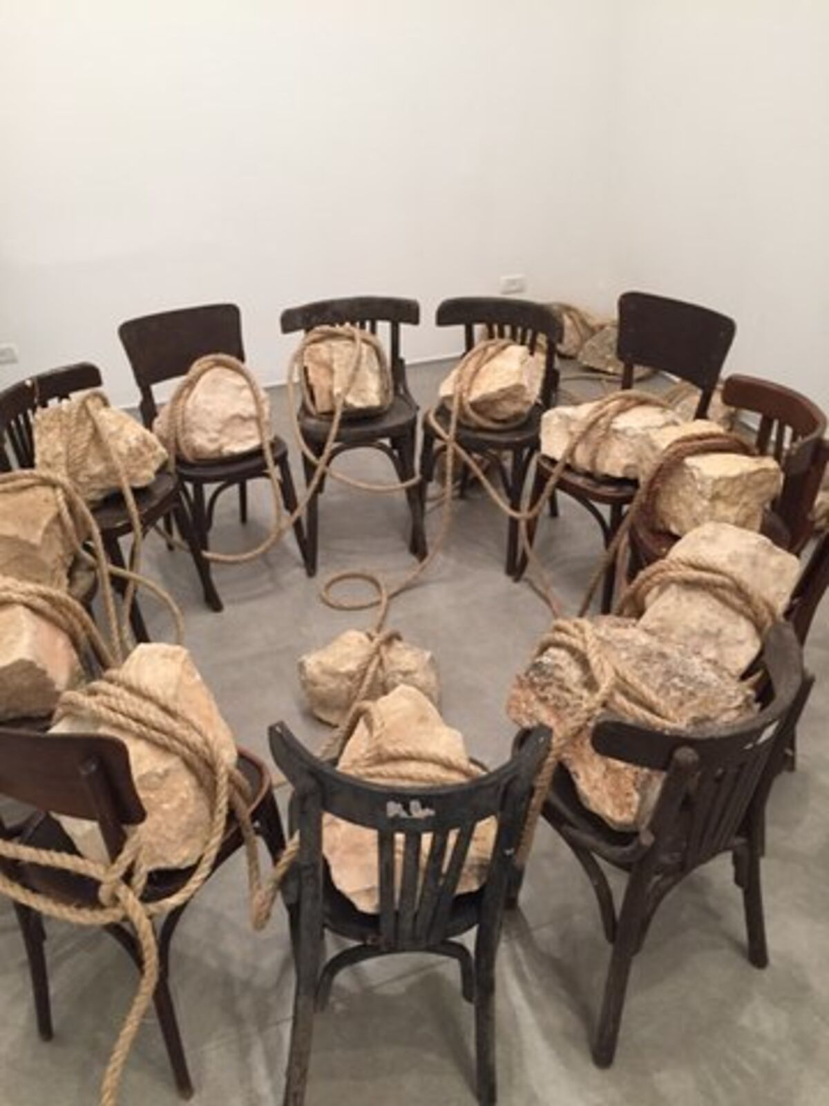 A group of wooden chairs tied up with rope in a room.