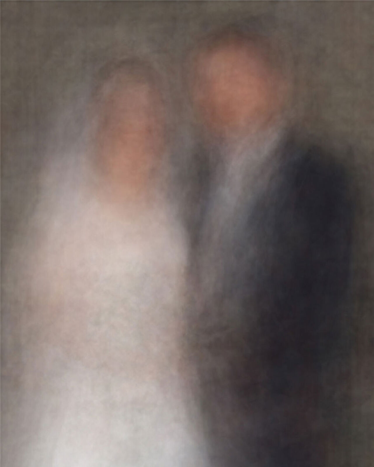 A blurred portrait of two figures embracing in a dark, intimate setting.