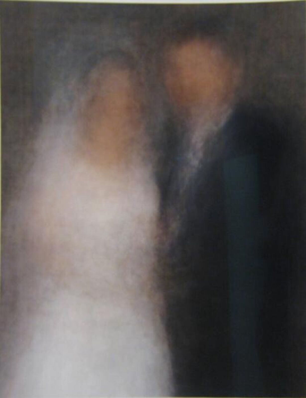 A blurred portrait of two figures embracing in a dark, intimate setting.
