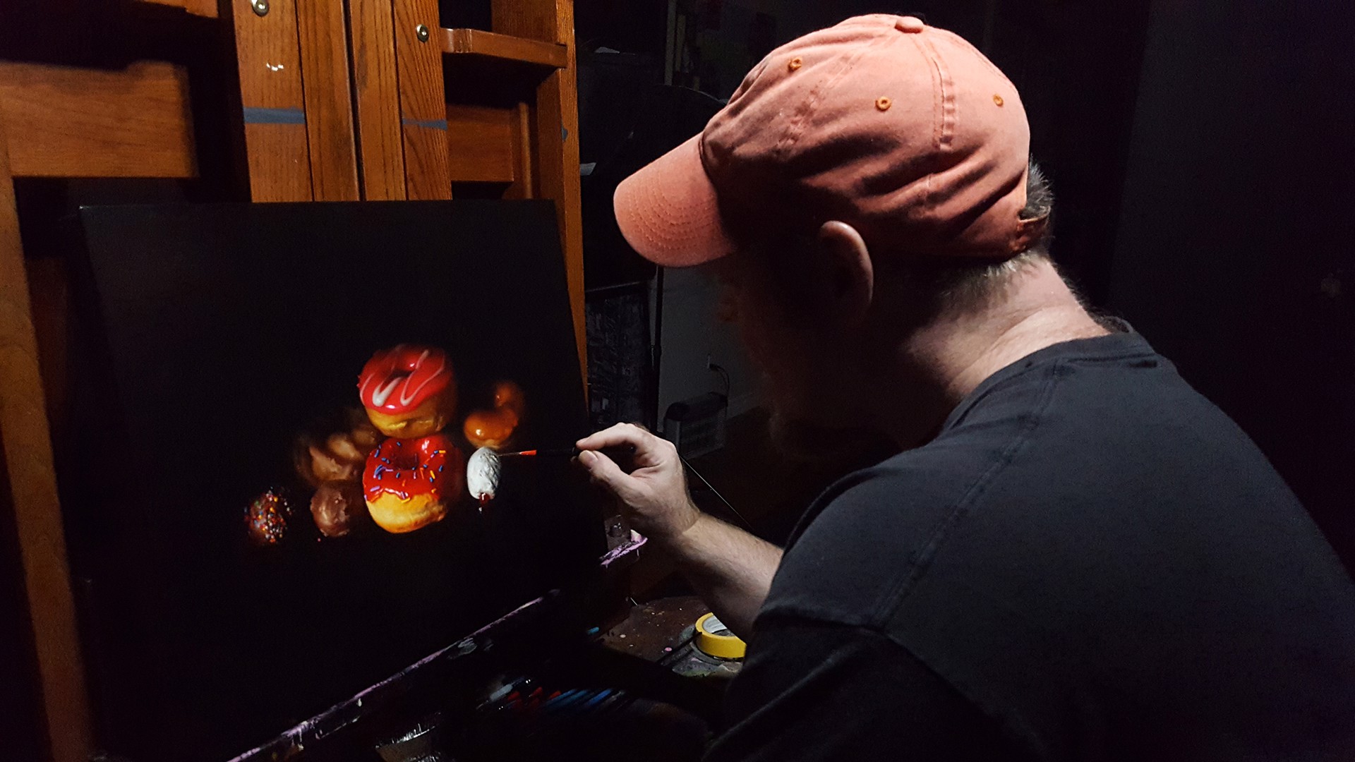 A still life arrangement of colorful donuts and pastries against a dark background.