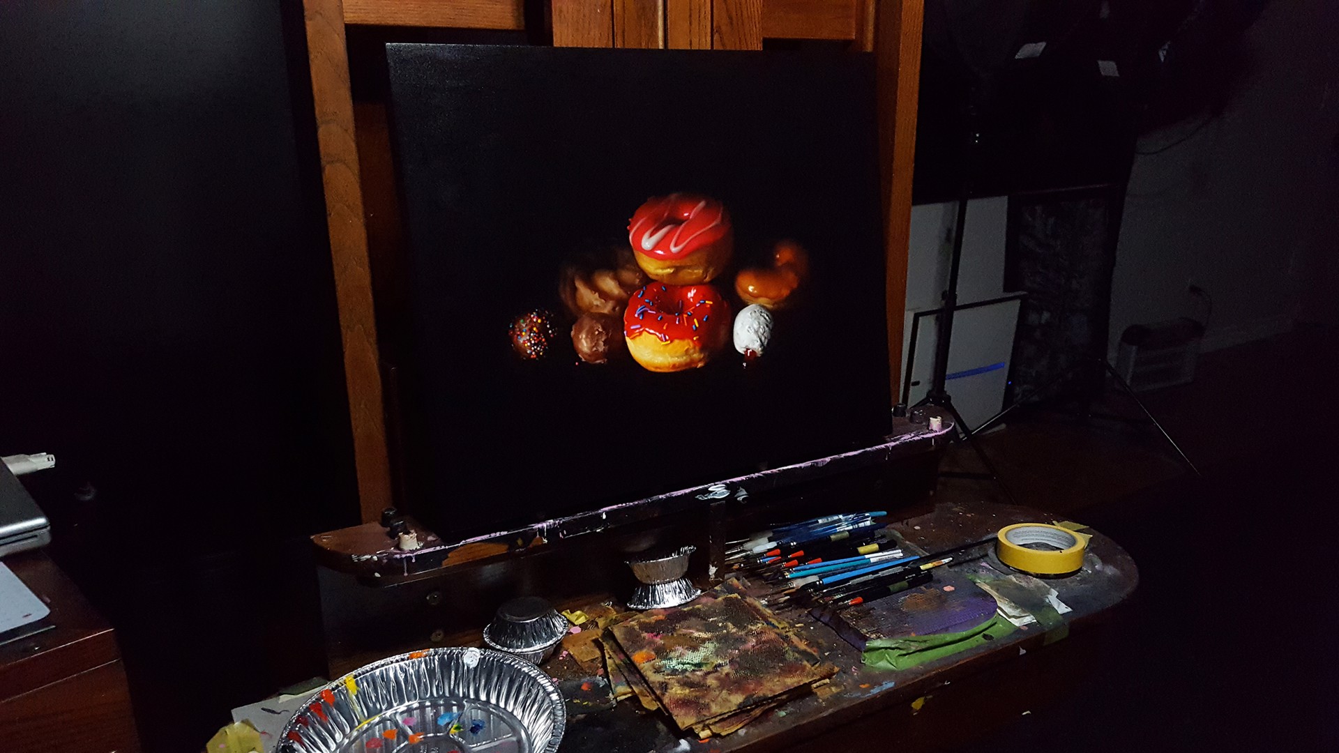 A still life arrangement of colorful donuts and pastries against a dark background.