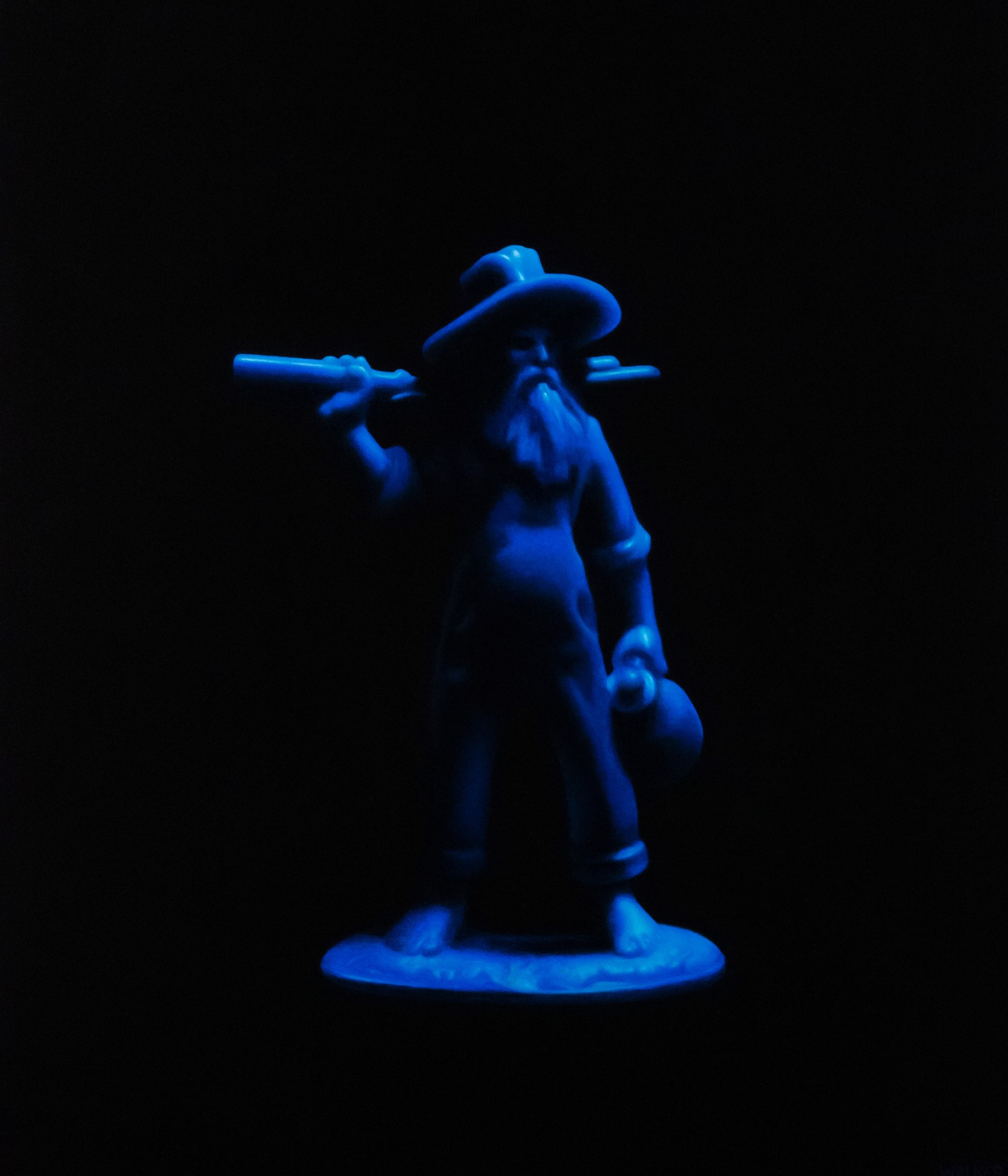 A glowing blue statue of a figure with a hat and long beard, holding a staff and a lantern.