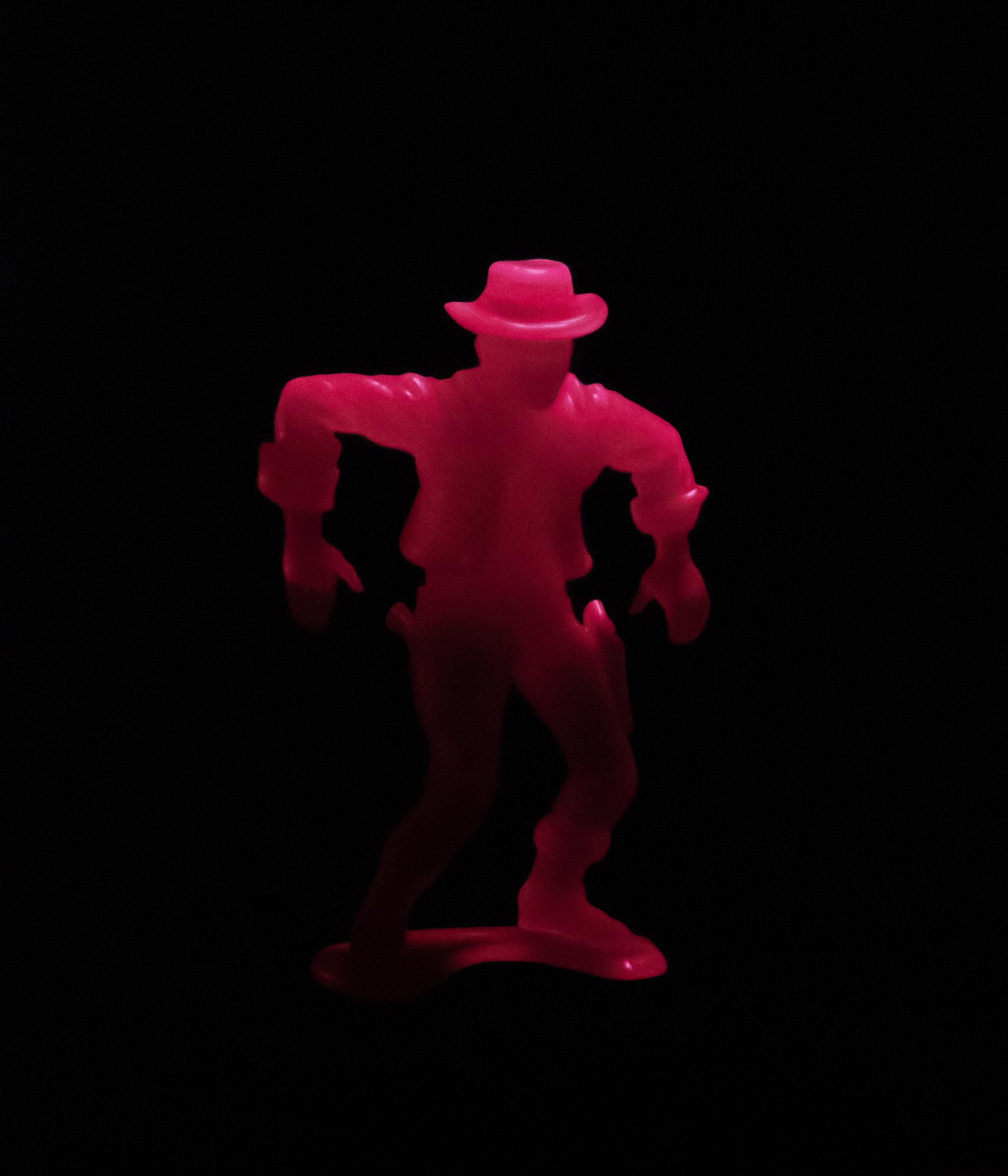 A pink toy figure of a man with a hat on.