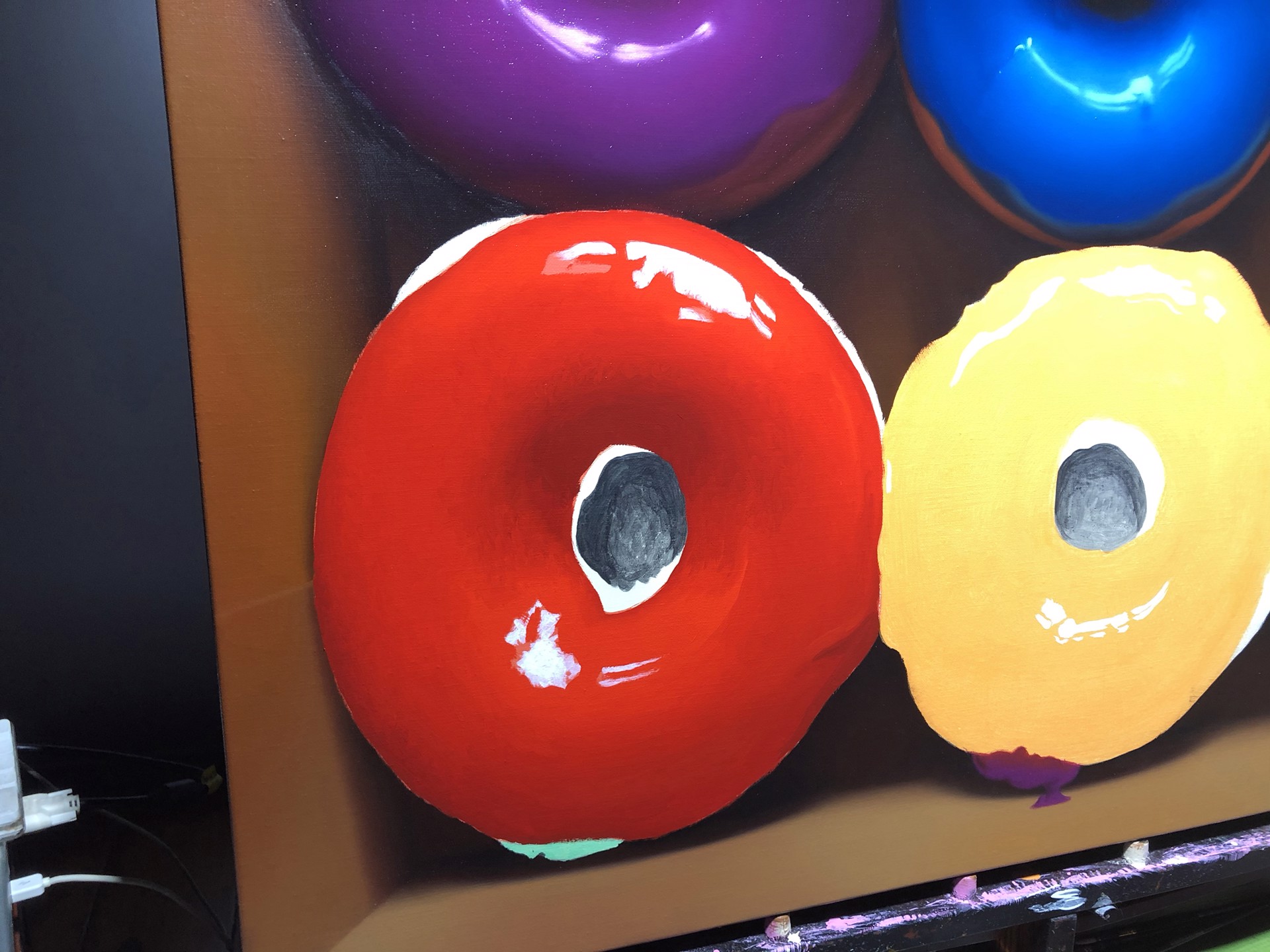 A vibrant display of six colorful glazed donuts arranged in two rows within a cardboard box.