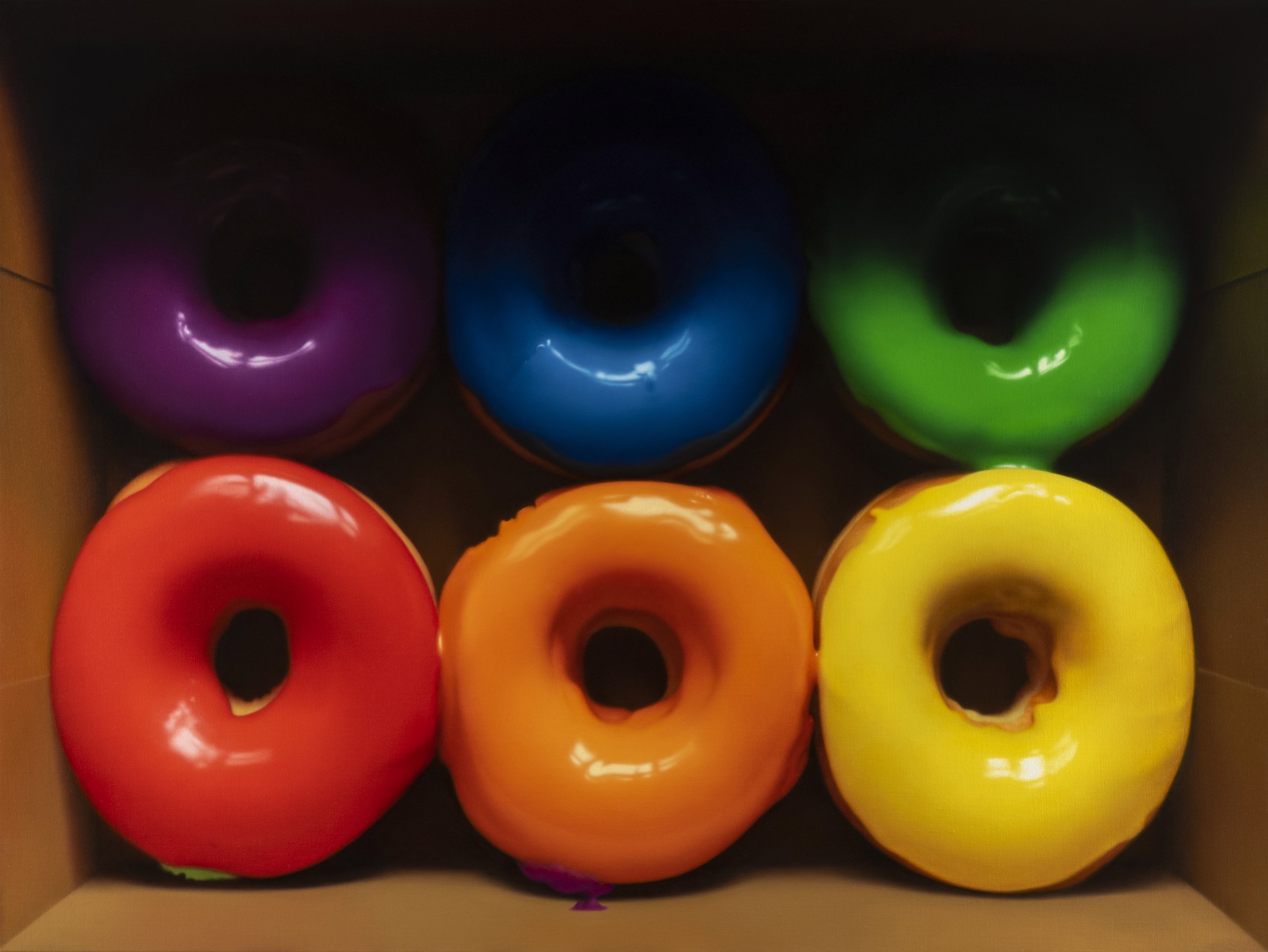 A vibrant display of six colorful glazed donuts arranged in two rows within a cardboard box.