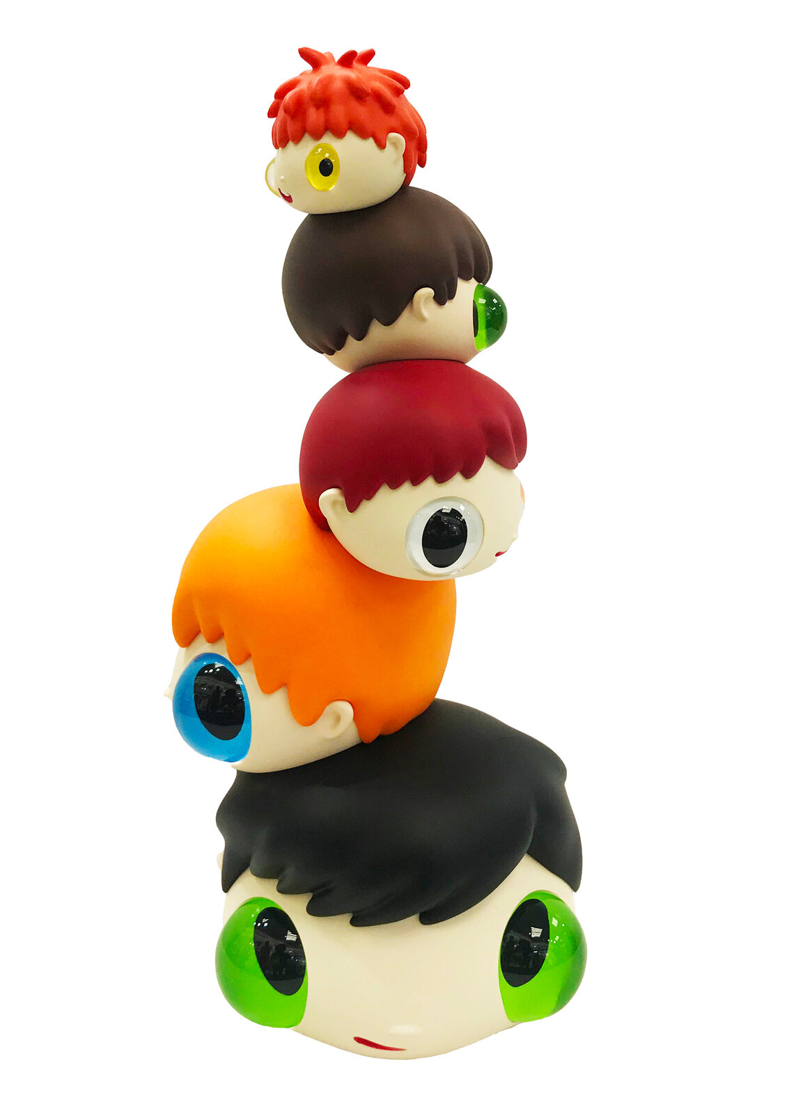 A whimsical stack of colorful, oversized heads with mismatched eyes sits beside a tall black box.