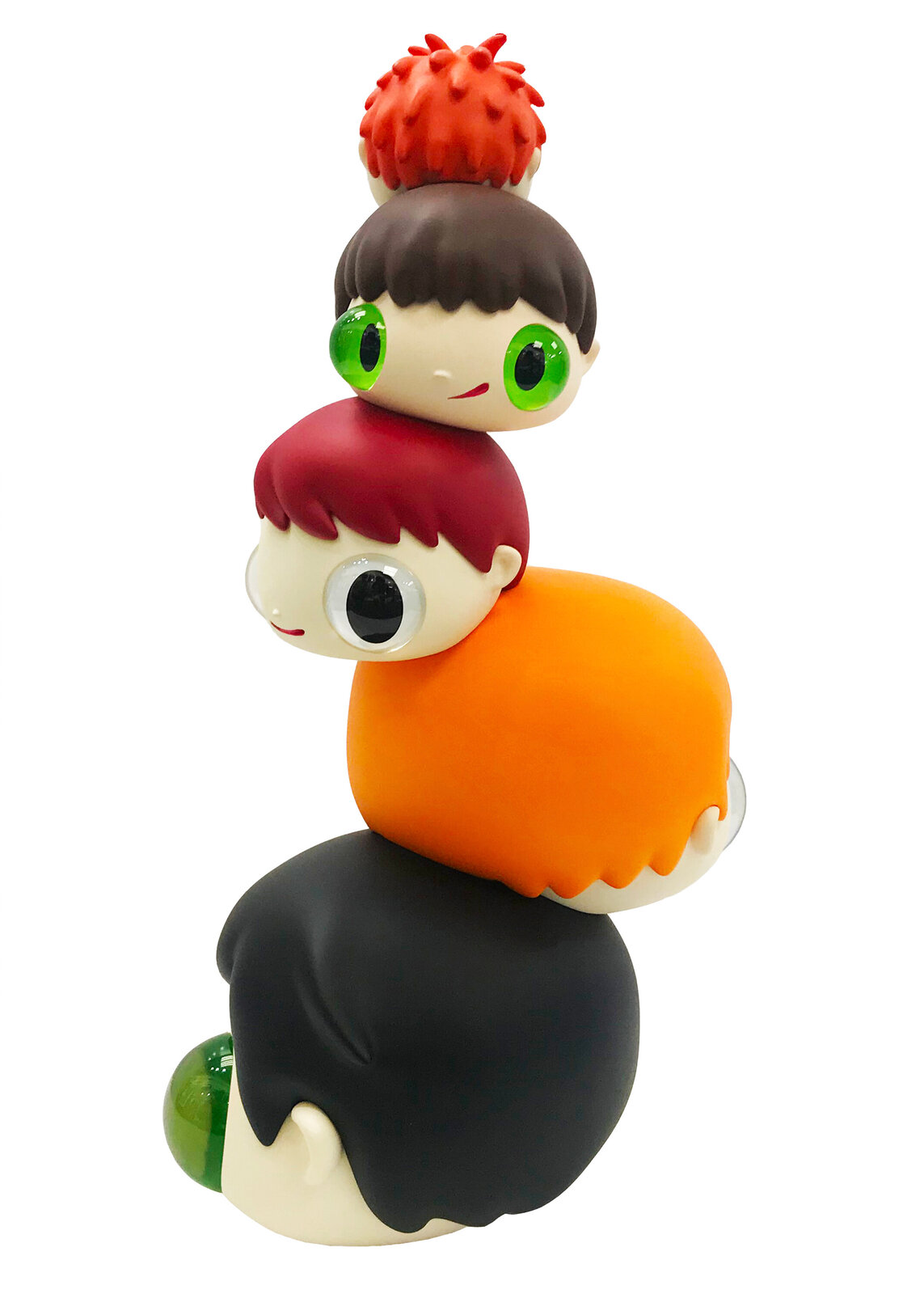 A whimsical stack of colorful, oversized heads with mismatched eyes sits beside a tall black box.