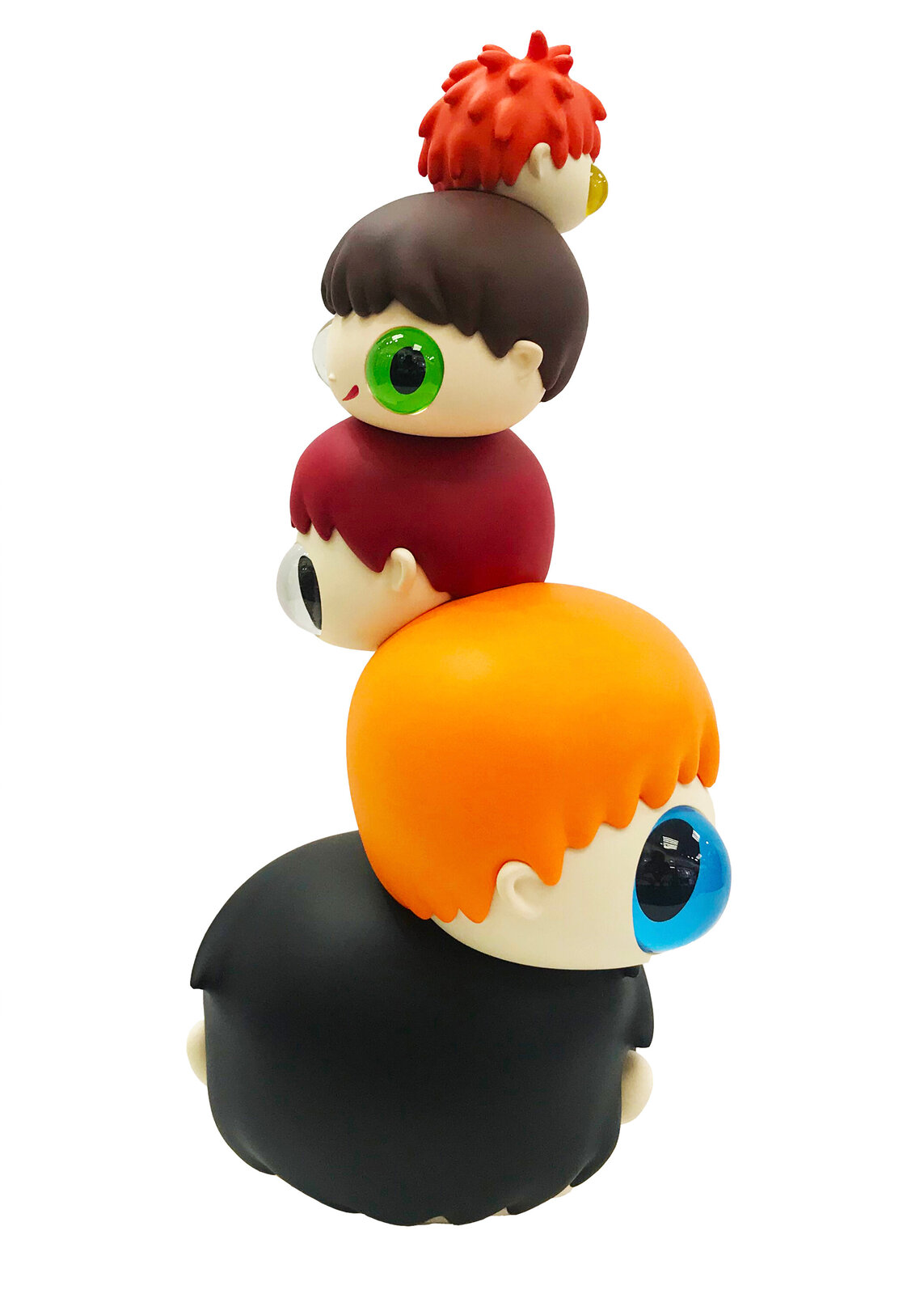 A whimsical stack of colorful, oversized heads with mismatched eyes sits beside a tall black box.