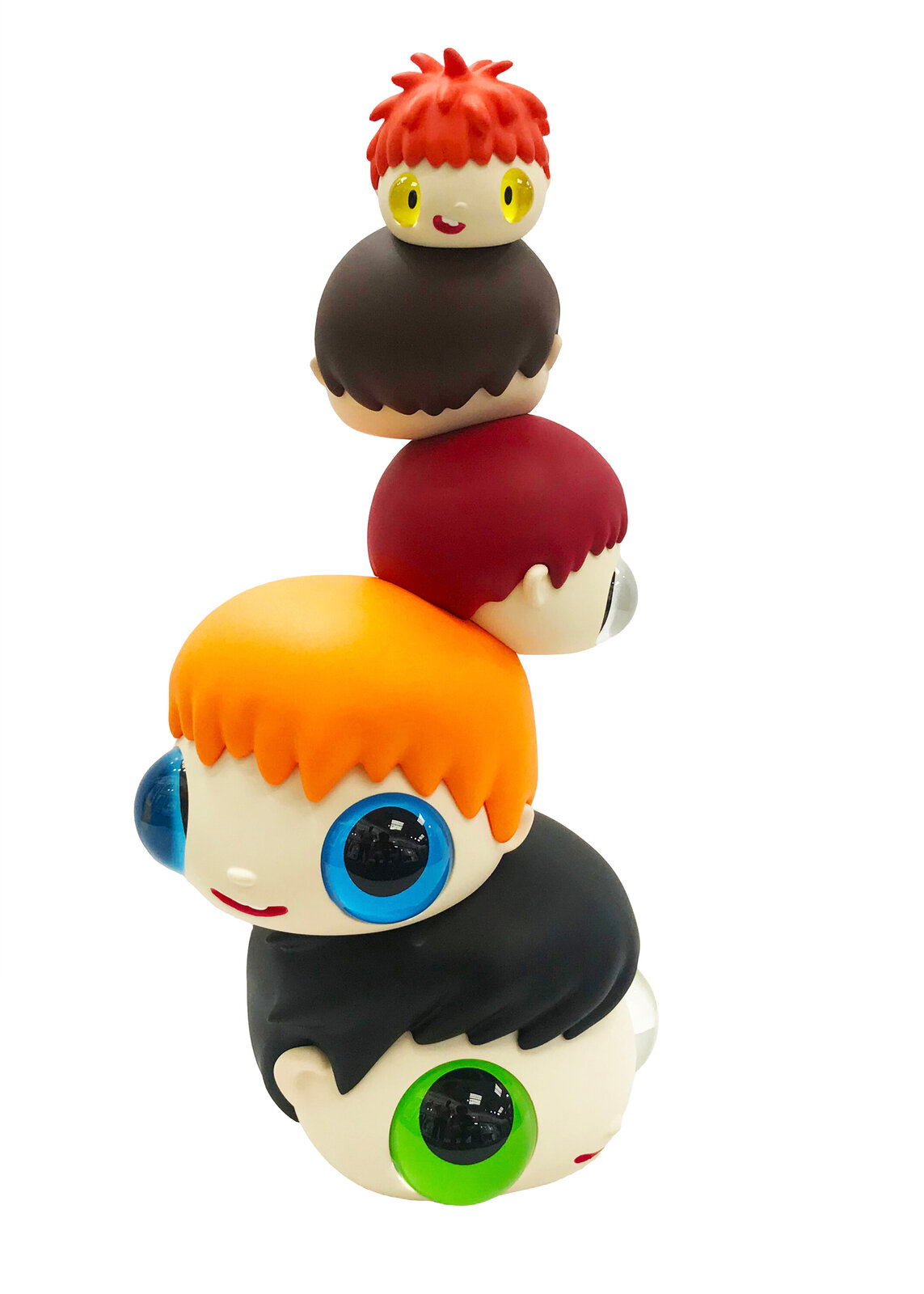 A whimsical stack of colorful, oversized heads with mismatched eyes sits beside a tall black box.