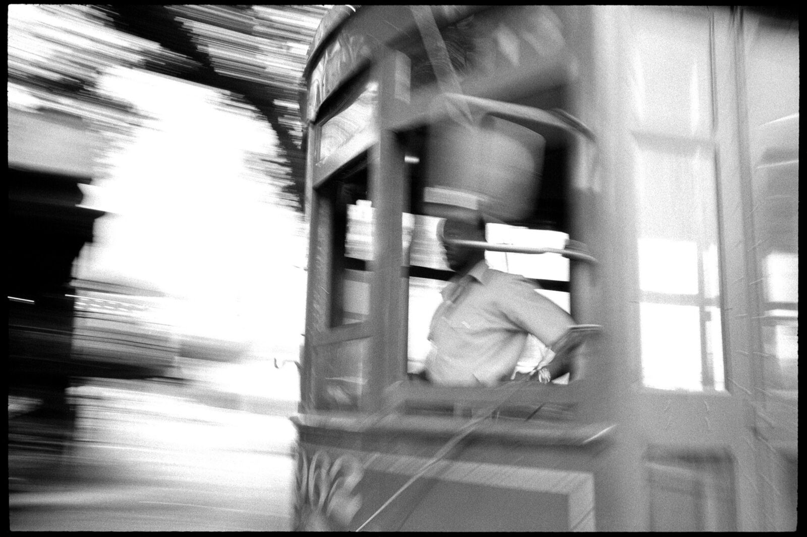 A black and white photo of a man in a trolley car.
