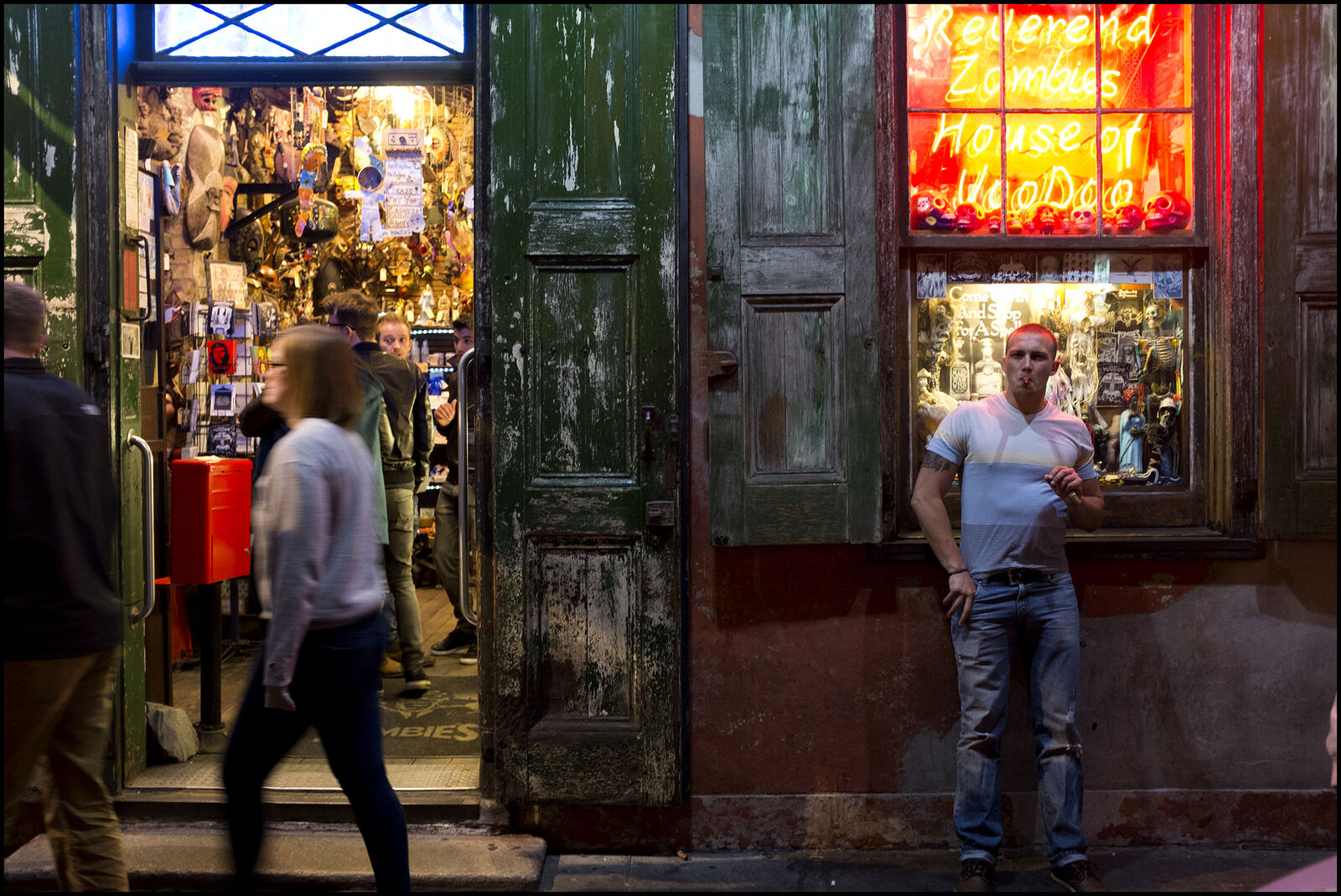 A man standing in front of a store at night.