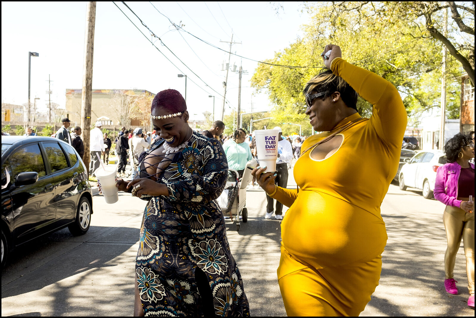 A woman in a yellow dress and a woman in black and white dress walking down the street.