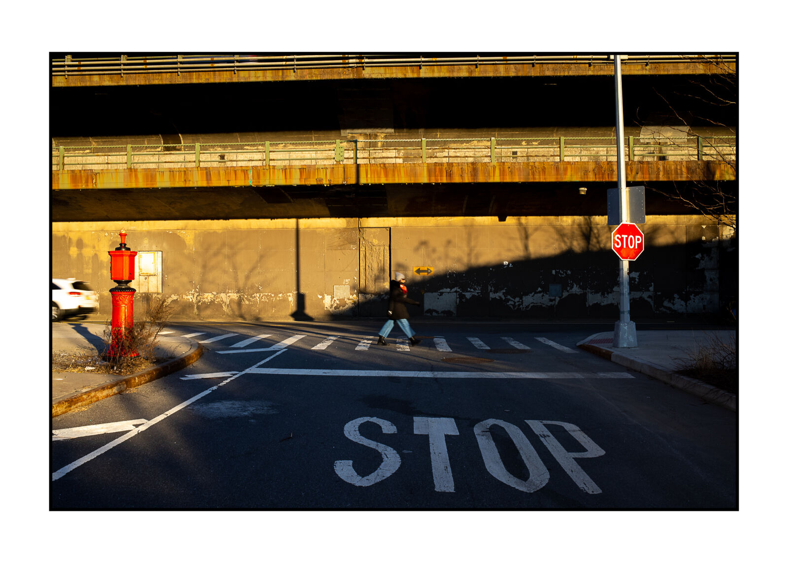 A person walking across a street next to a stop sign.