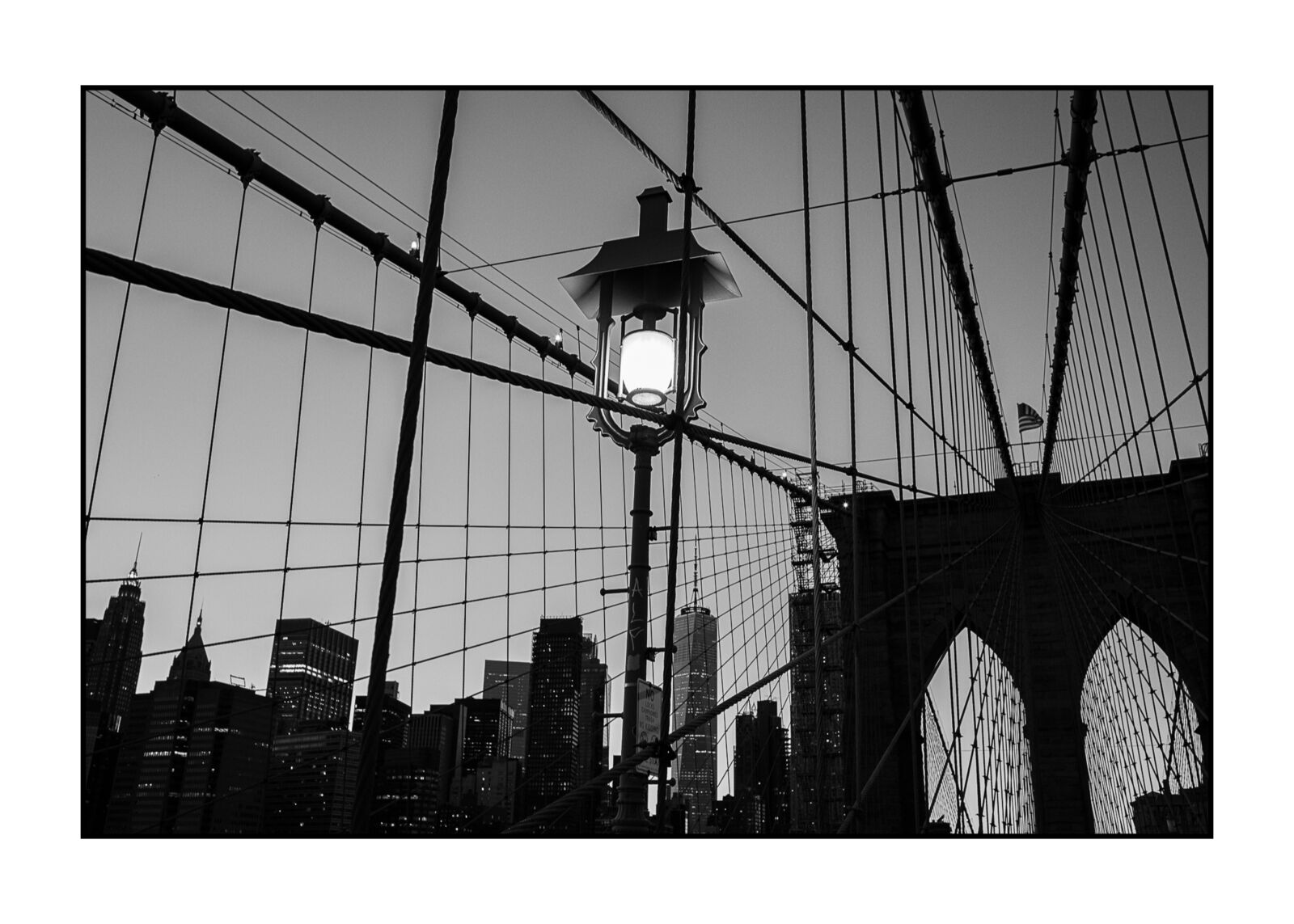 A black and white photo of a street light on a bridge.