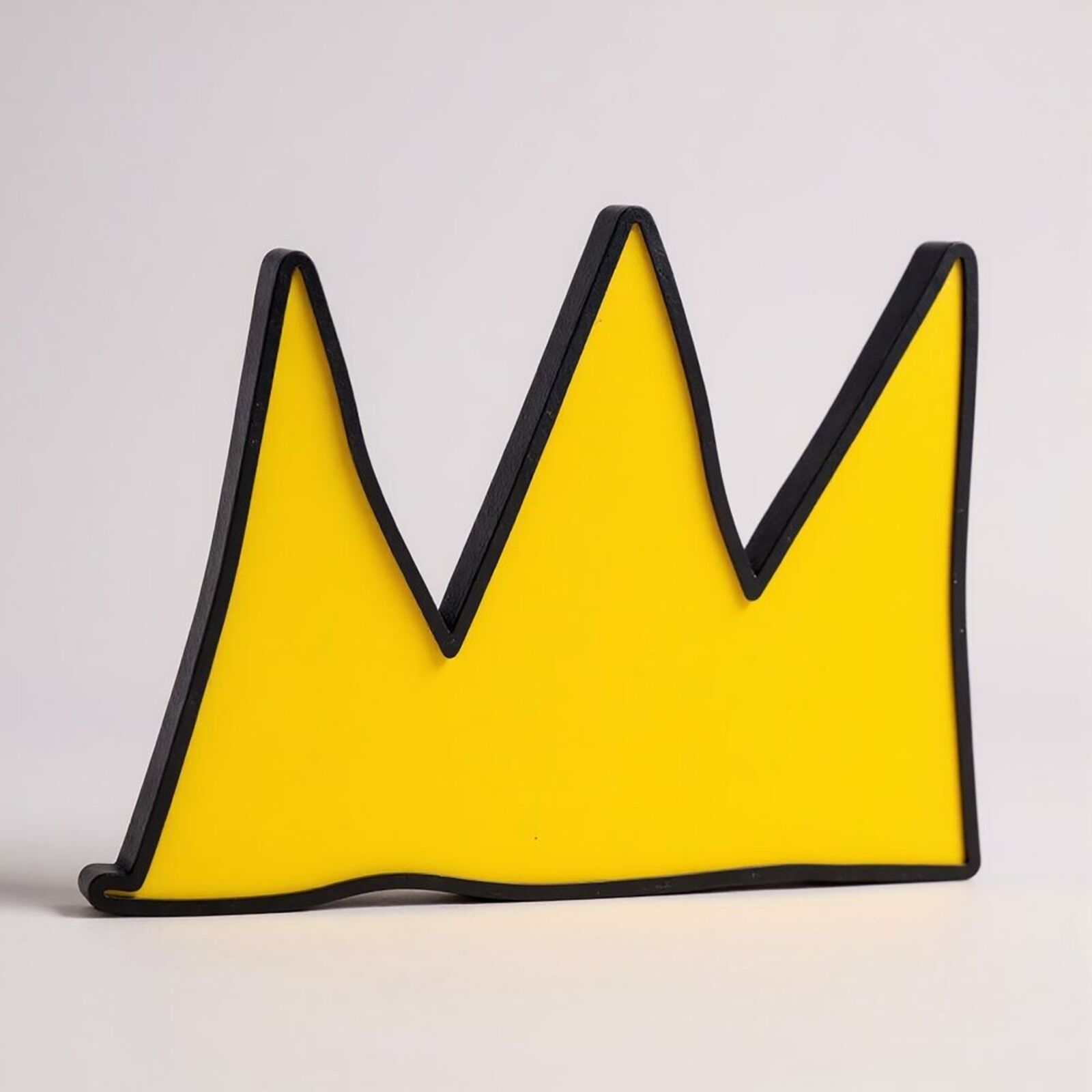 A yellow and black crown shaped object on a white surface.