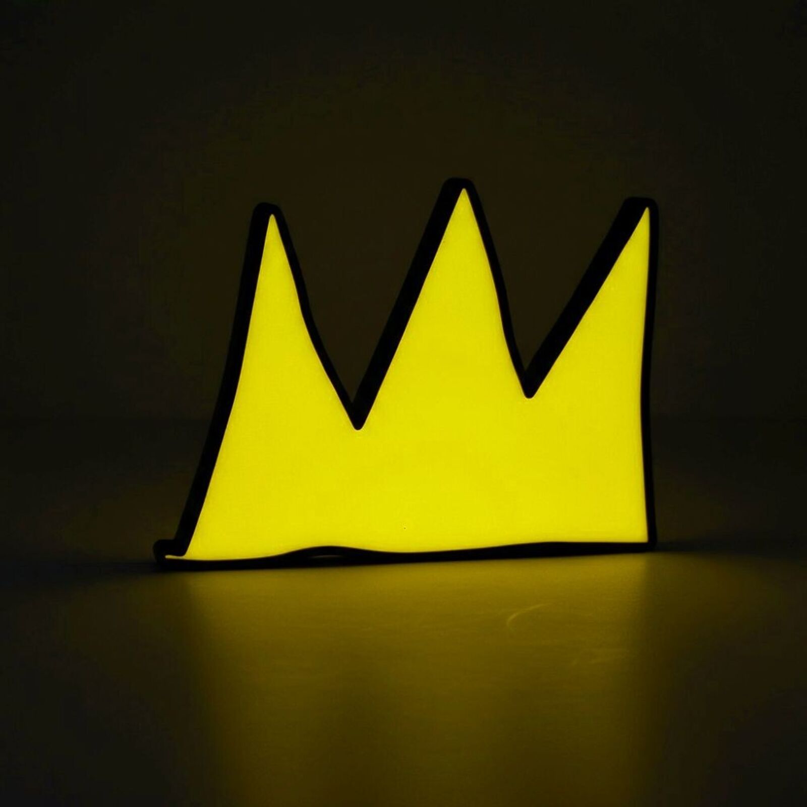 A yellow and black crown shaped object on a white surface.