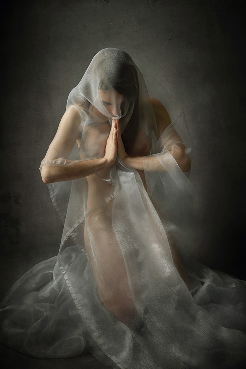 A woman in a white dress with a veil covering her face.