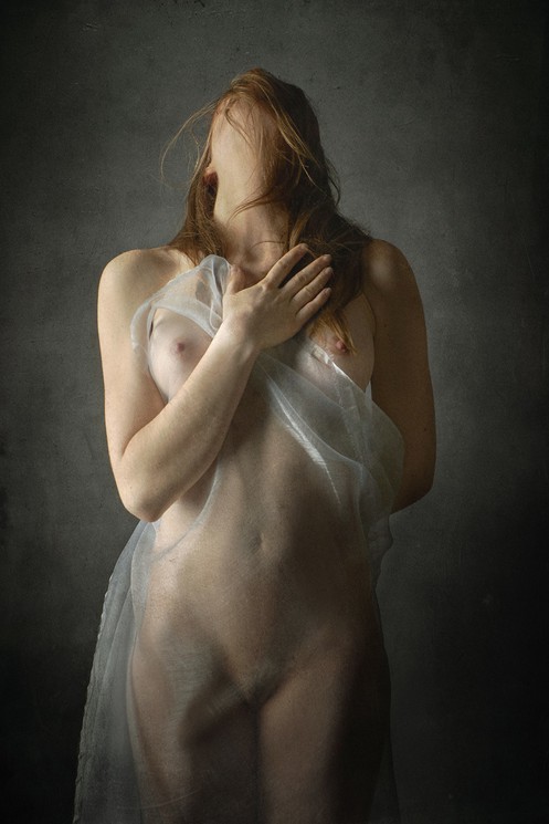 A nude woman in a white dress is posing for a picture.