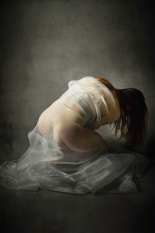 A woman in a white dress is sitting on the ground.