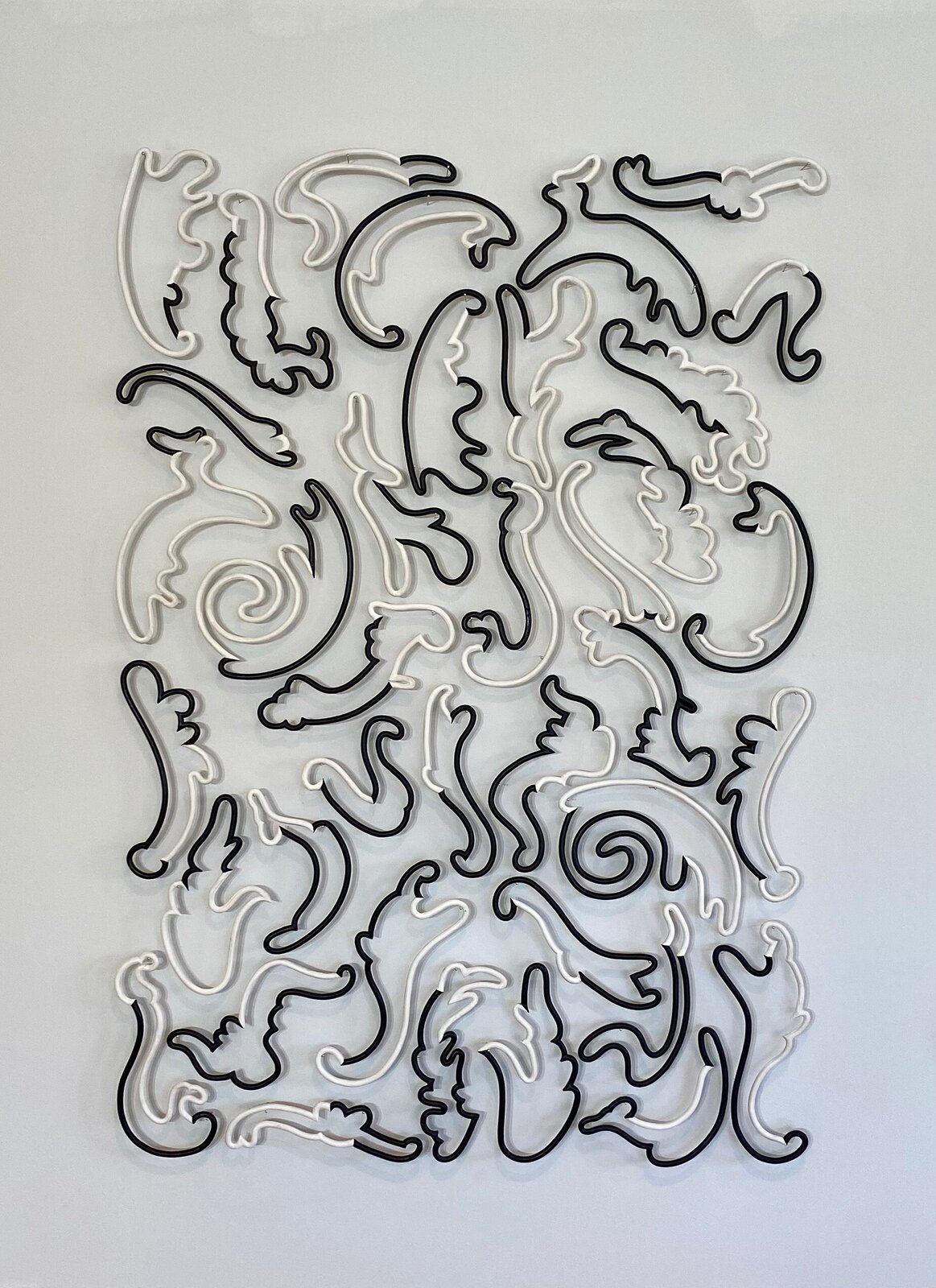 A monochrome wall installation featuring intertwined black and white scrollwork forms.